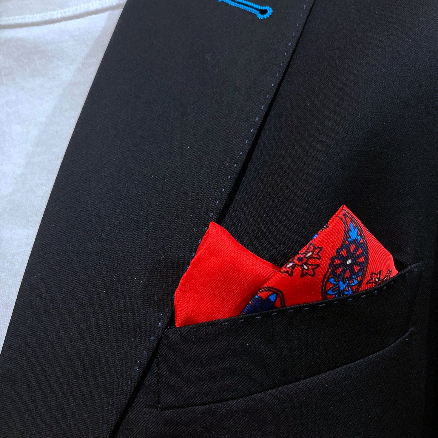 Close-up of 'Casablanca' silk pocket square in breast pocket of dark suit jacket.