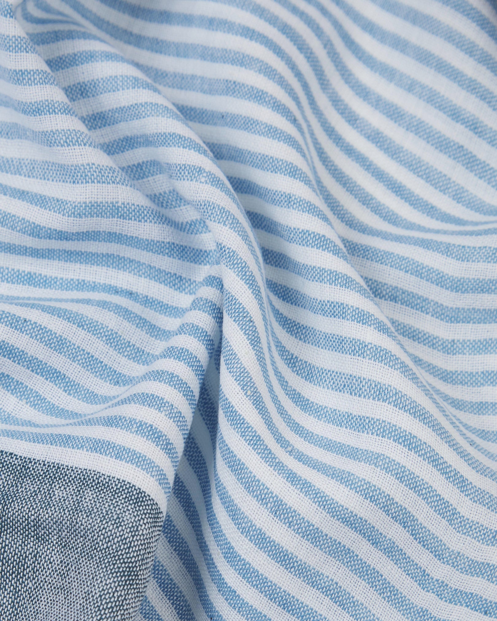 Ruffled close-up view of the UK-made, pure cotton 'Adams' scarf, presenting a closer view of the blue, brown and white yarns which make up the striped, patchwork-style pattern.