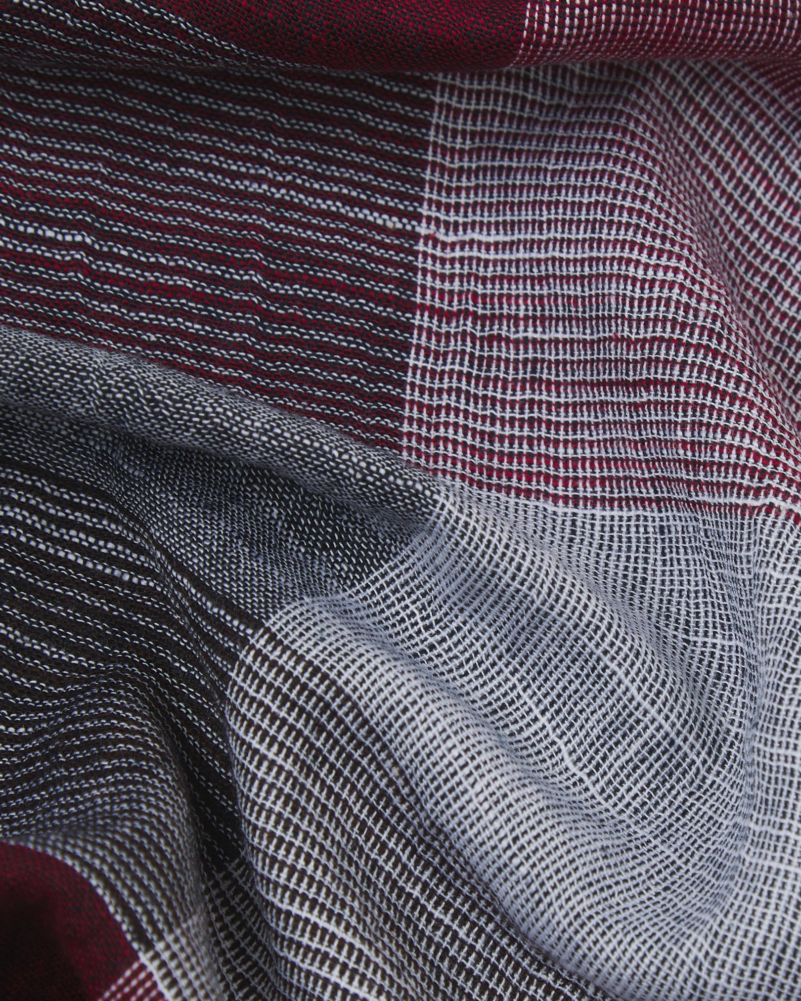 Ruffled close-up view of the UK-made, pure cotton 'Fiennes' scarf, presenting a closer view of the black, red and white yarns which make up the check pattern.