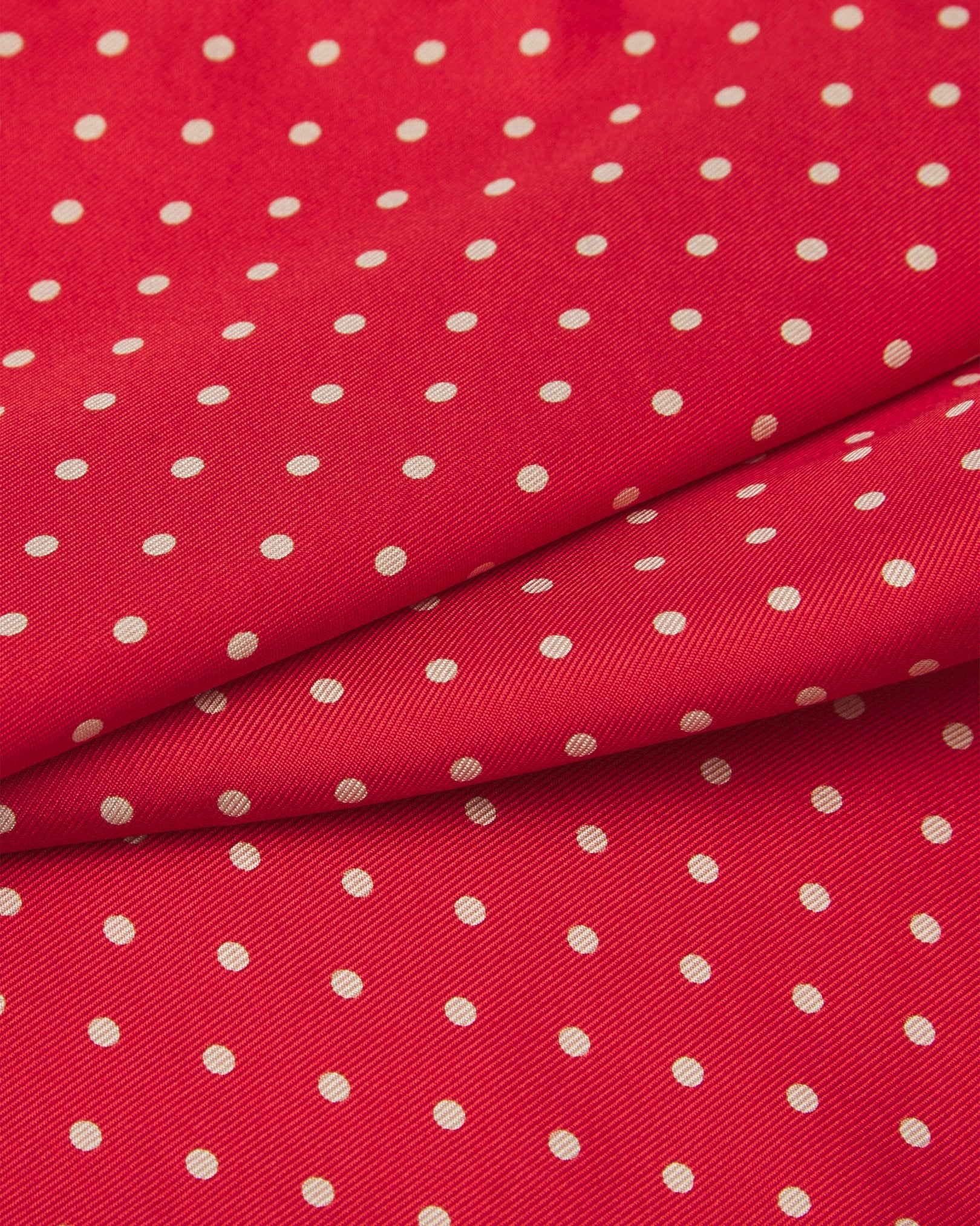 A ruffled close-up of the 'Hastings' pocket square, presenting a closer view of the white polka dots against a bright red background. 