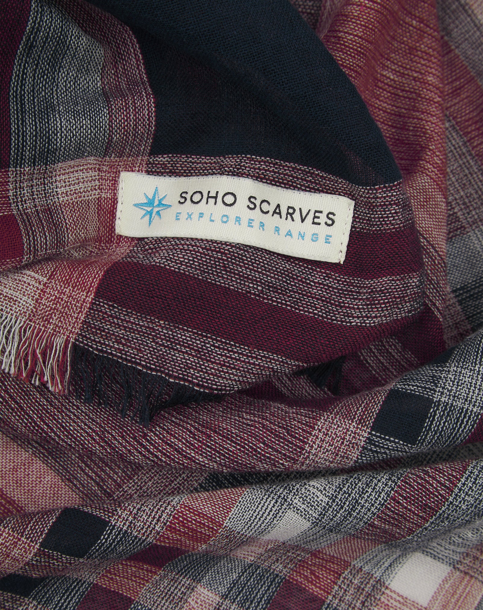 Ruffled close-up view of the pure cotton 'Hillary' scarf, presenting a closer view of the navy, red, and grey yarns which make up the Tartan pattern.