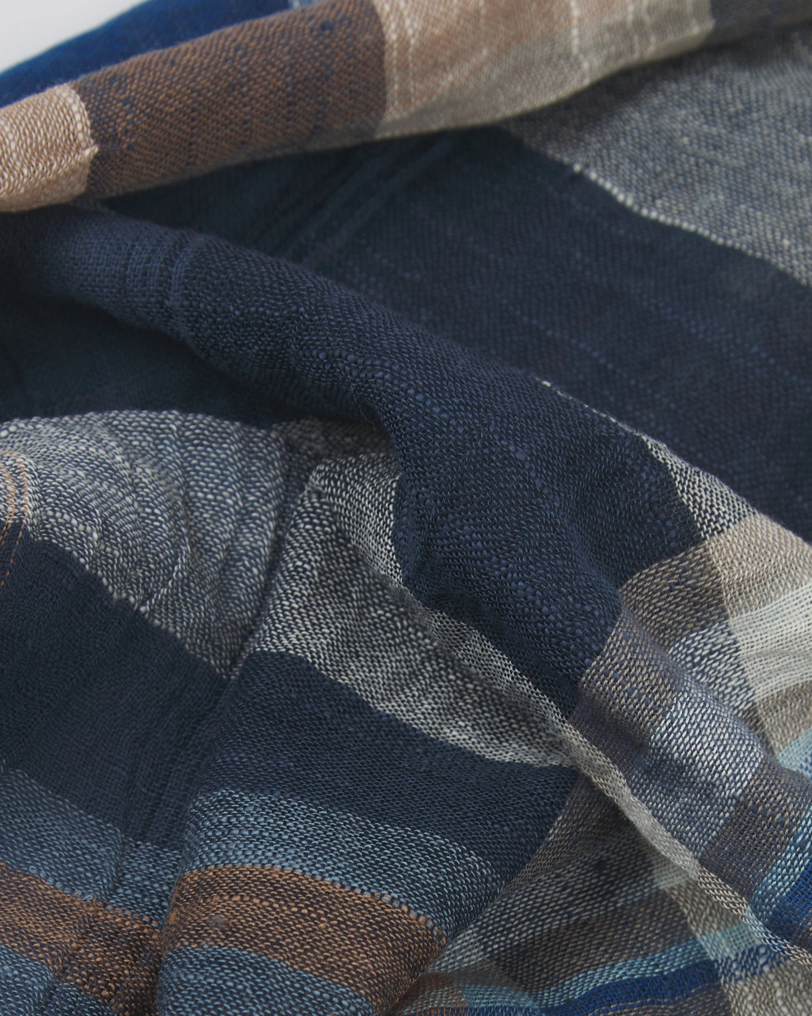 Ruffled close-up view of the UK-made, pure cotton 'Irvine' scarf, presenting a closer view of the brown, blue and white yarns which make up the attractive heathered tartan-like design.