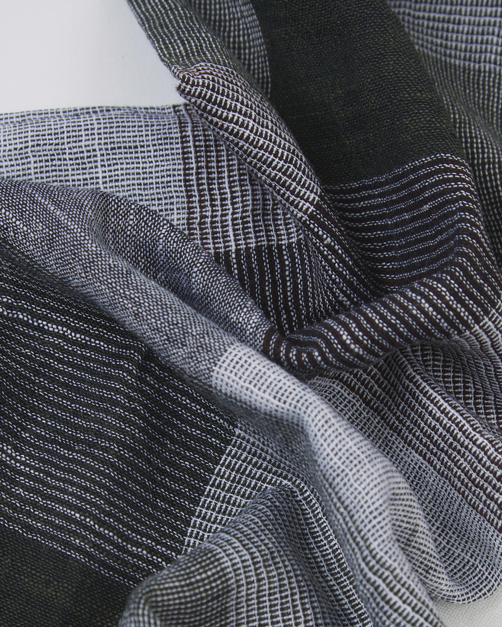 Ruffled close-up view of the UK-made, pure cotton 'Livingstone' scarf, presenting a closer view of the black and white yarns which make up the check pattern.