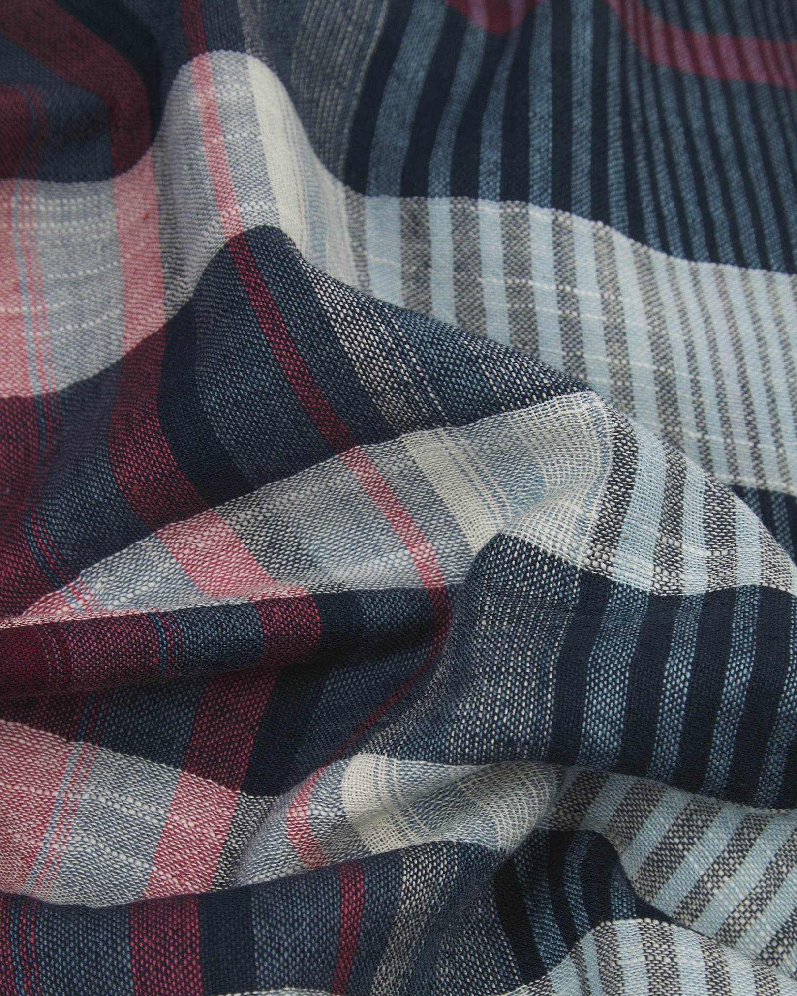 Ruffled close-up view of the UK-made, pure cotton 'MacInnes' scarf, presenting a closer view of the blue, red and white yarns which make up the attractive heathered tartan-like design.