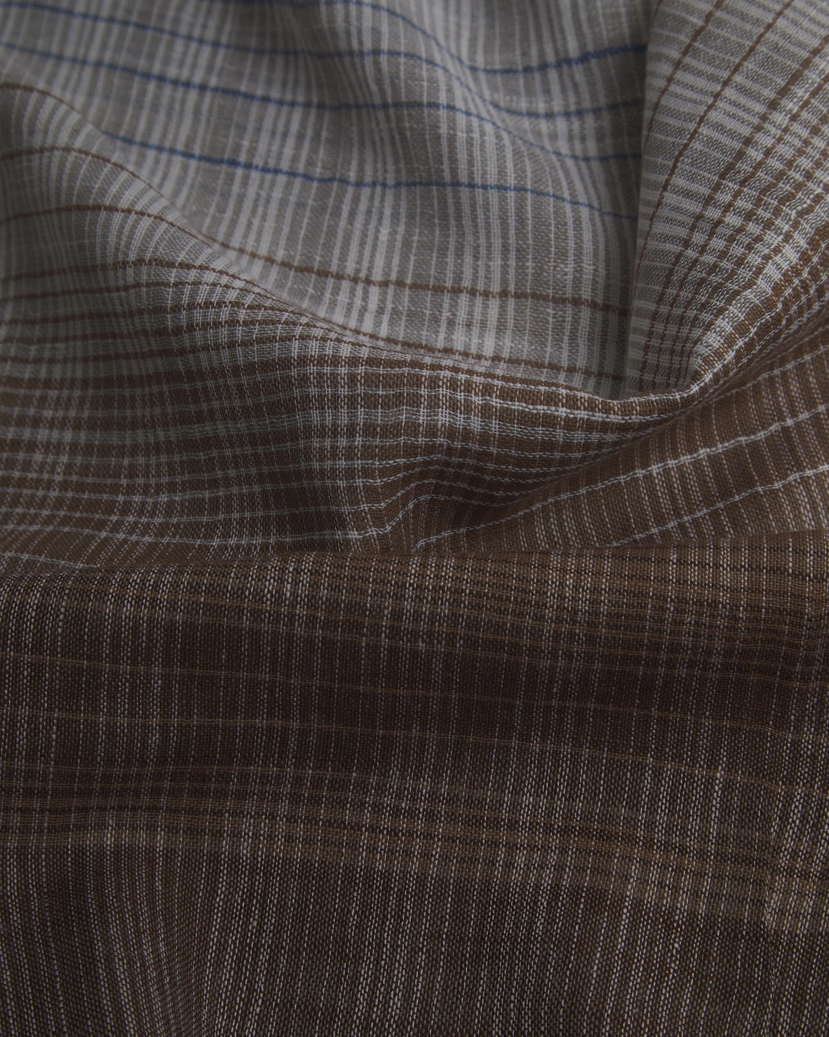 Ruffled close-up view of the UK-made, pure cotton 'Mallory' scarf, presenting a closer view of the brown and white yarns which make up the transitional, gradient pattern and thin stripes.