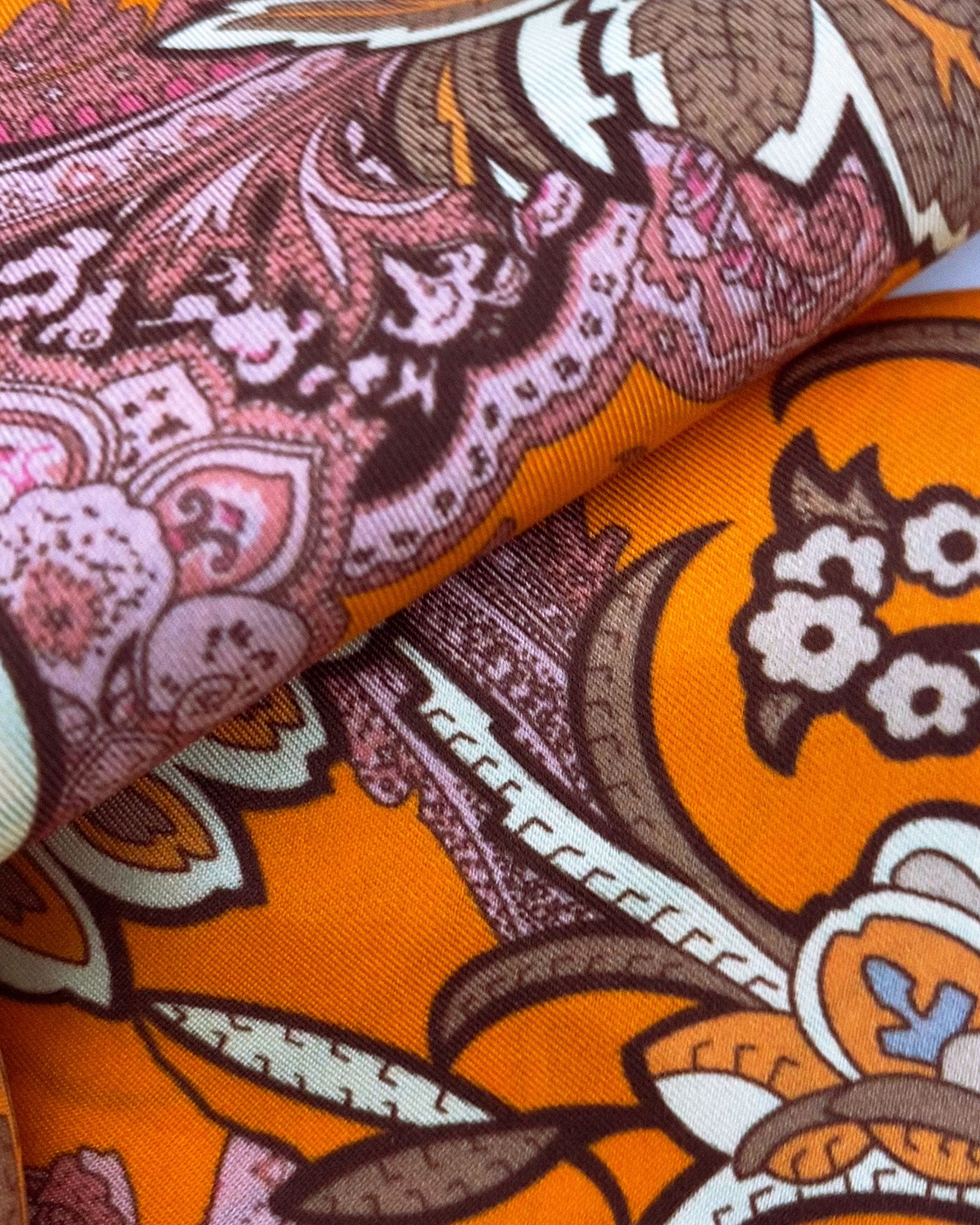 Ruffled close-up view of the Niagra silk scarf, presenting a closer view of the pink and orange floral-paisley leaves and flower repeats.