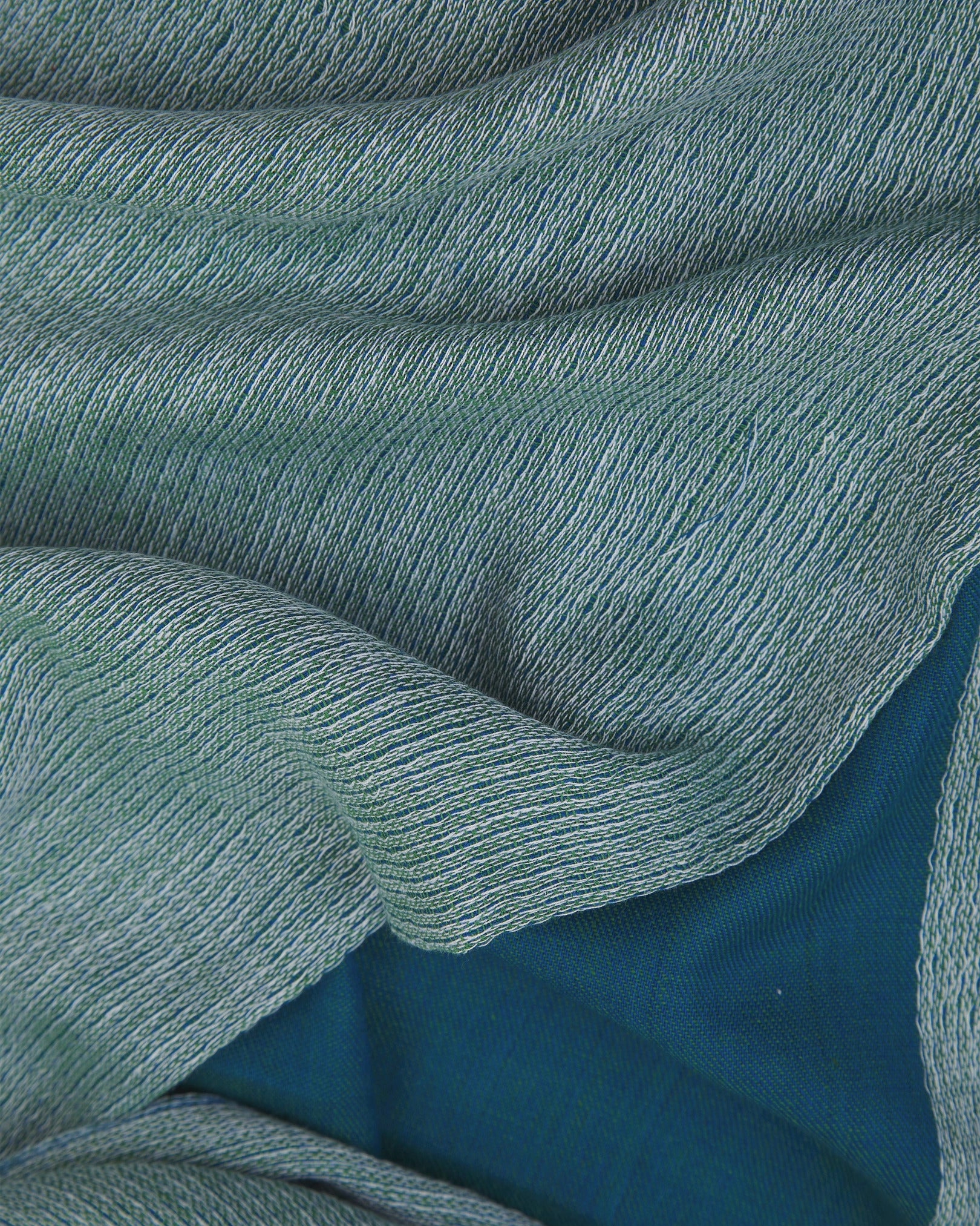 Ruffled close-up view of the UK-made, pure cotton 'Saunders' scarf, presenting a closer view of the blue and green yarns which make up the marled, two-tone style.