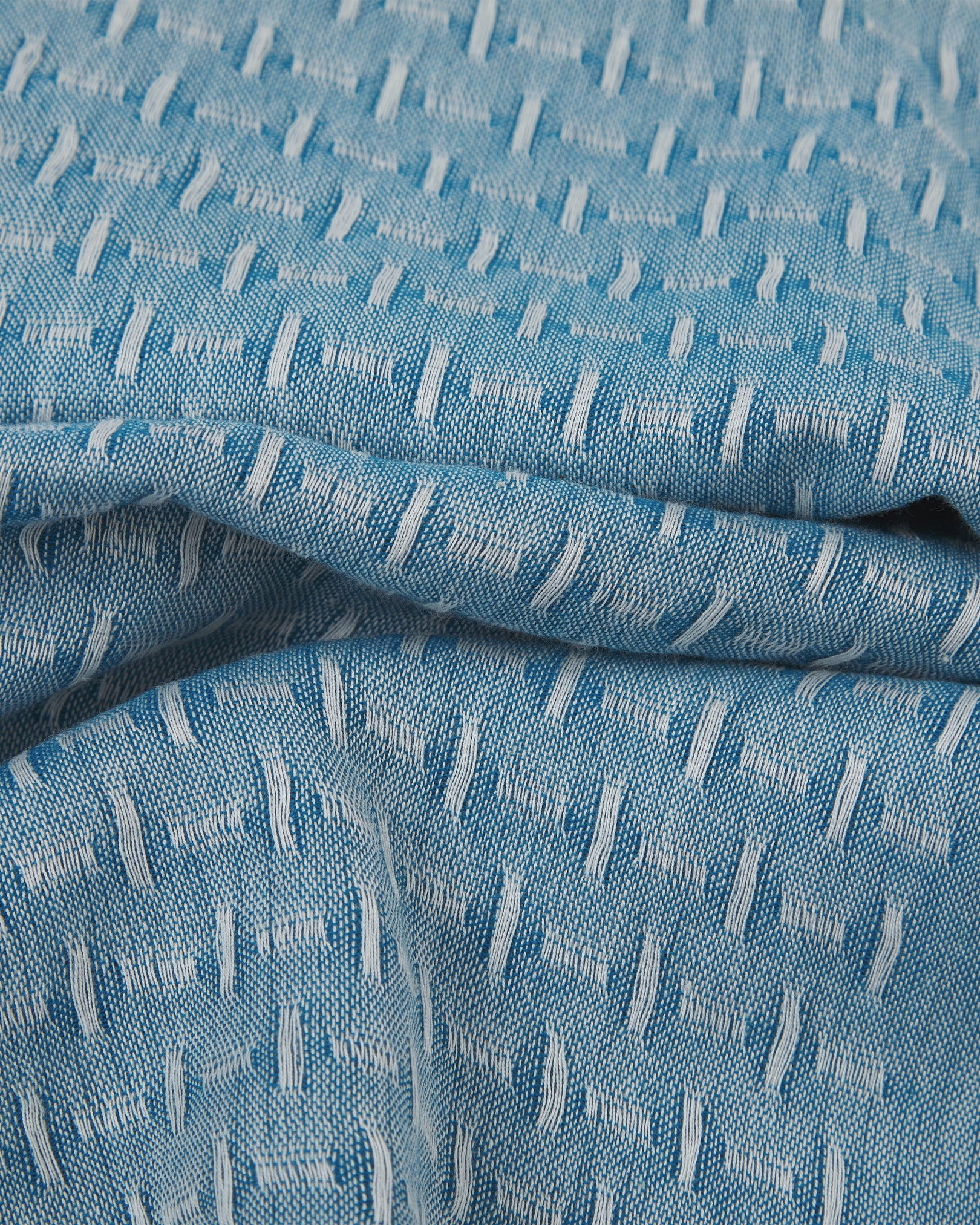 Ruffled close-up view of the UK-made, pure cotton 'Shackleton' scarf, presenting a closer view of the repeat blue and white pattern of vertical and horizontal dashes