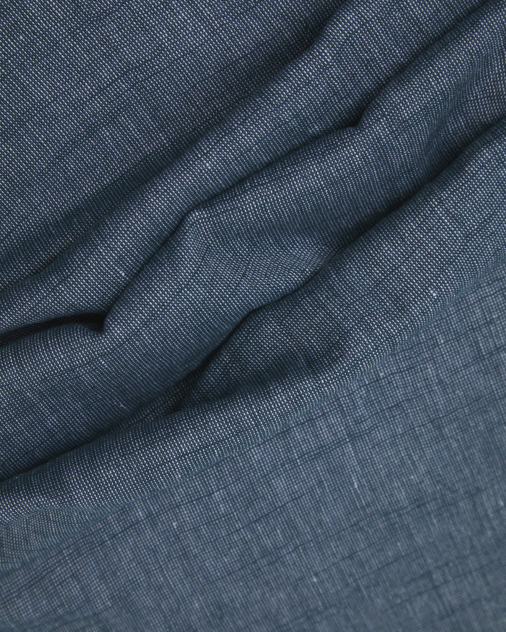 Ruffled close-up view of the UK-made, pure cotton 'Sharman' scarf, presenting a closer view of the navy and white yarns which make up the marled blue-grey effect.