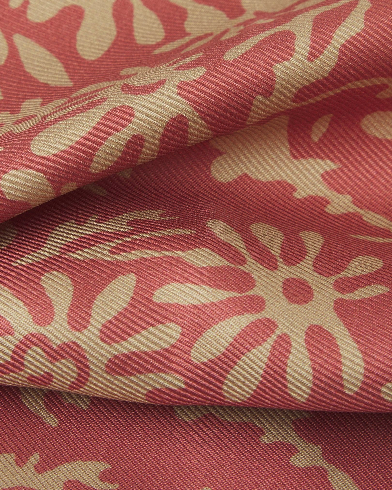 A ruffled close-up of the 'stonehenge' pocket square, presenting a closer view of the cream patterns against the attractive lustre of the salmon pink material. 