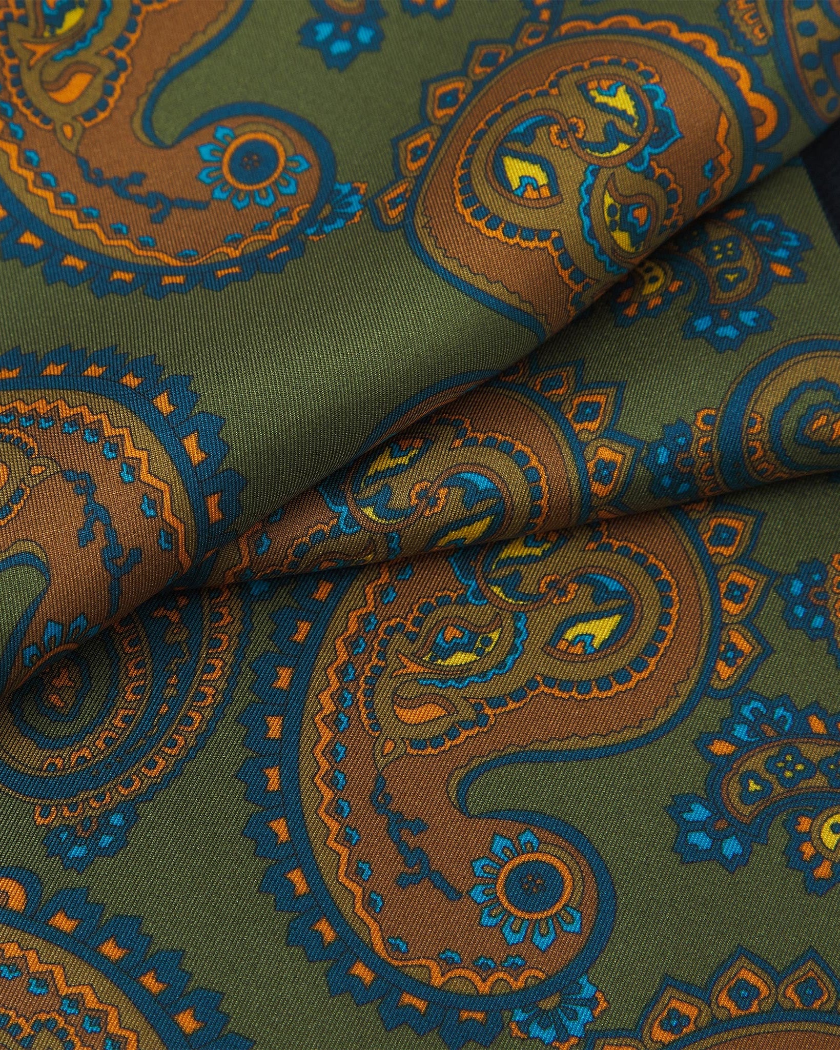 Ruffled close-up view of the Carlisle silk scarf, presenting a closer view of the orange paisley patterns enhanced with blue and gold accents against a rich green background