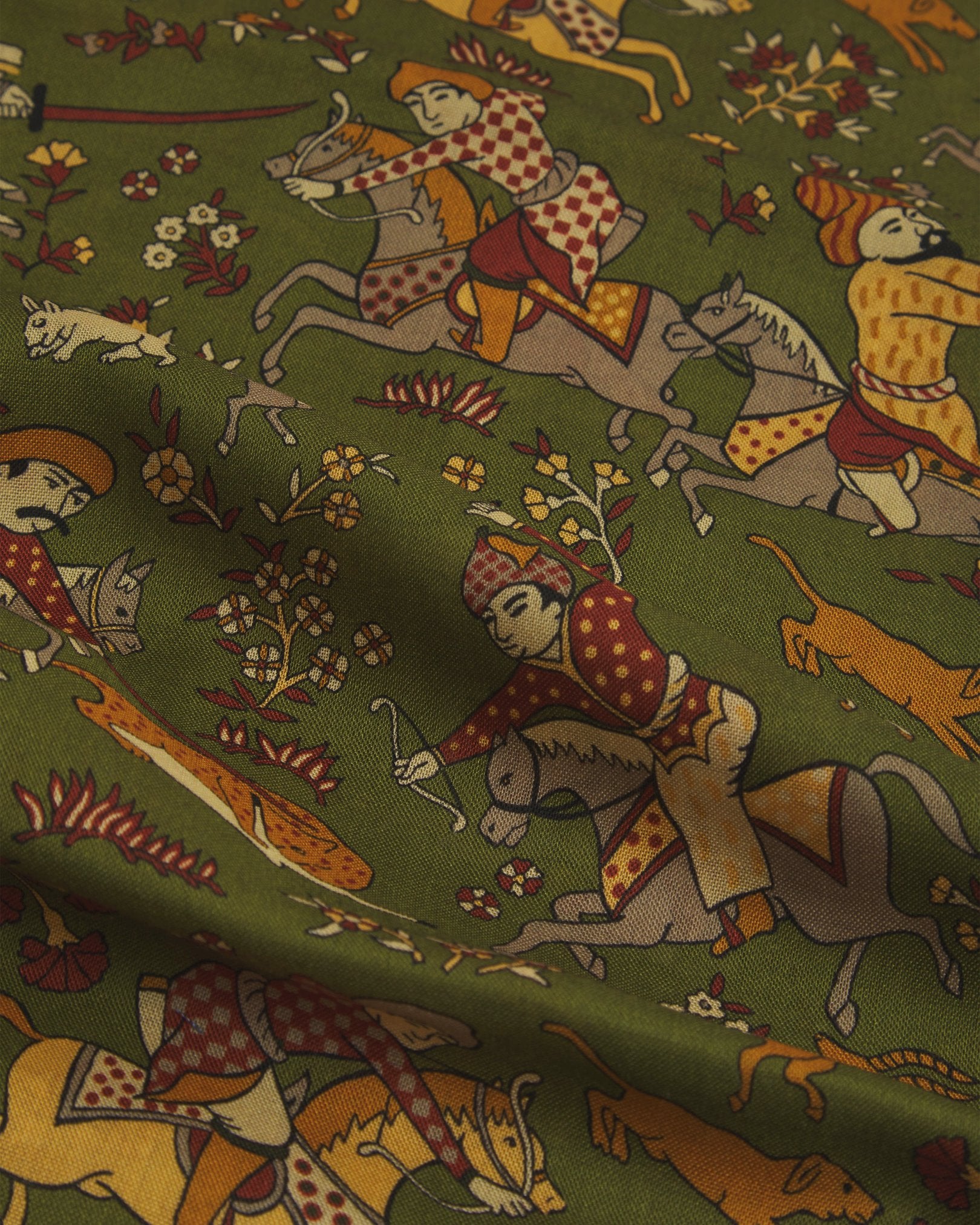 A flat, close-up view of the UK-made ‘olive green’ silk-wool scarf with ancient far-eastern hunting scenes. Clearly showing the premium silk and wool weave and the detailed multicoloured animal and floral patterns against a green background.