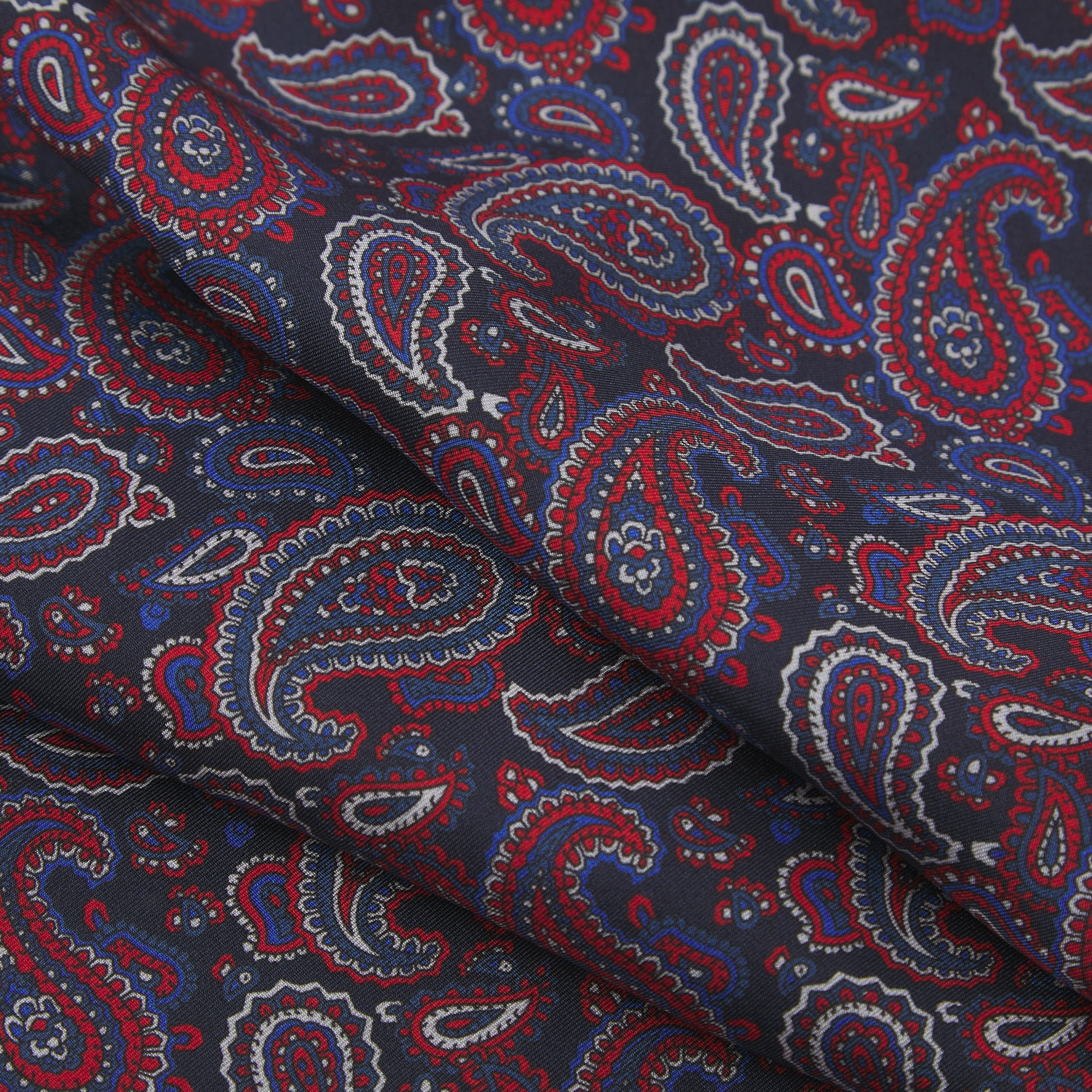 Ruffled close-up view of the Oakland silk scarf, presenting a closer view of the red, white and royal blue paisley patterns.