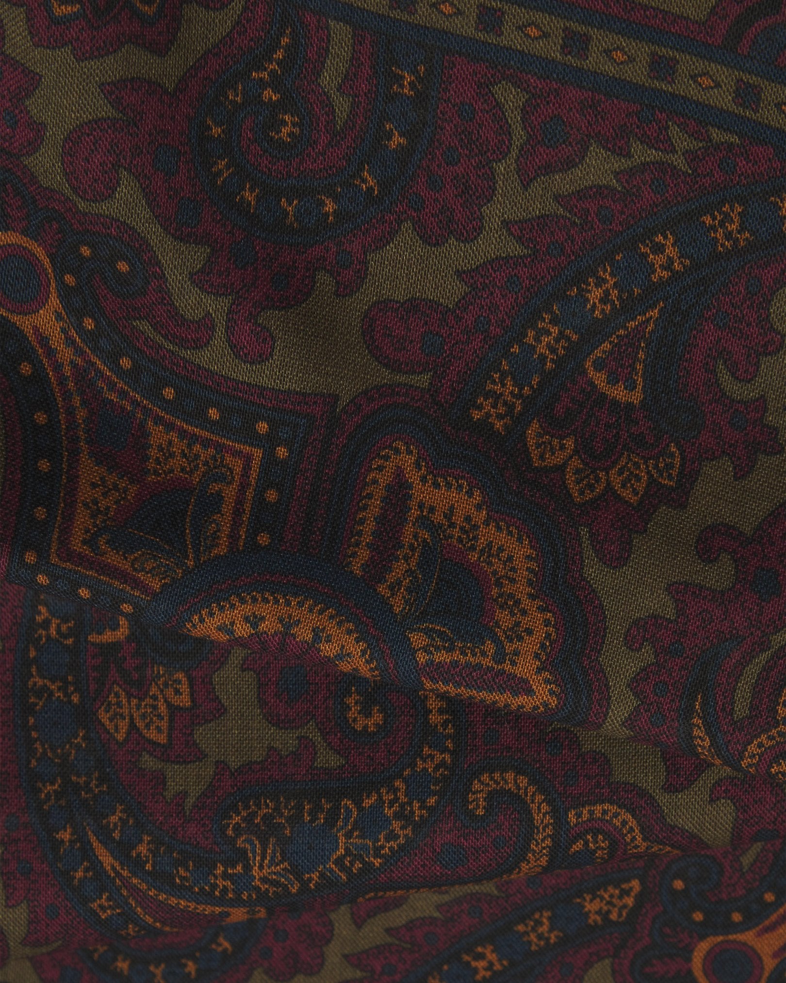 A flat, close-up view of the UK-made ‘highland green’ paisley silk-wool scarf. Clearly showing the premium silk and wool weave and the detailed gold, burgundy and navy paisley patterns against a highland-green background.