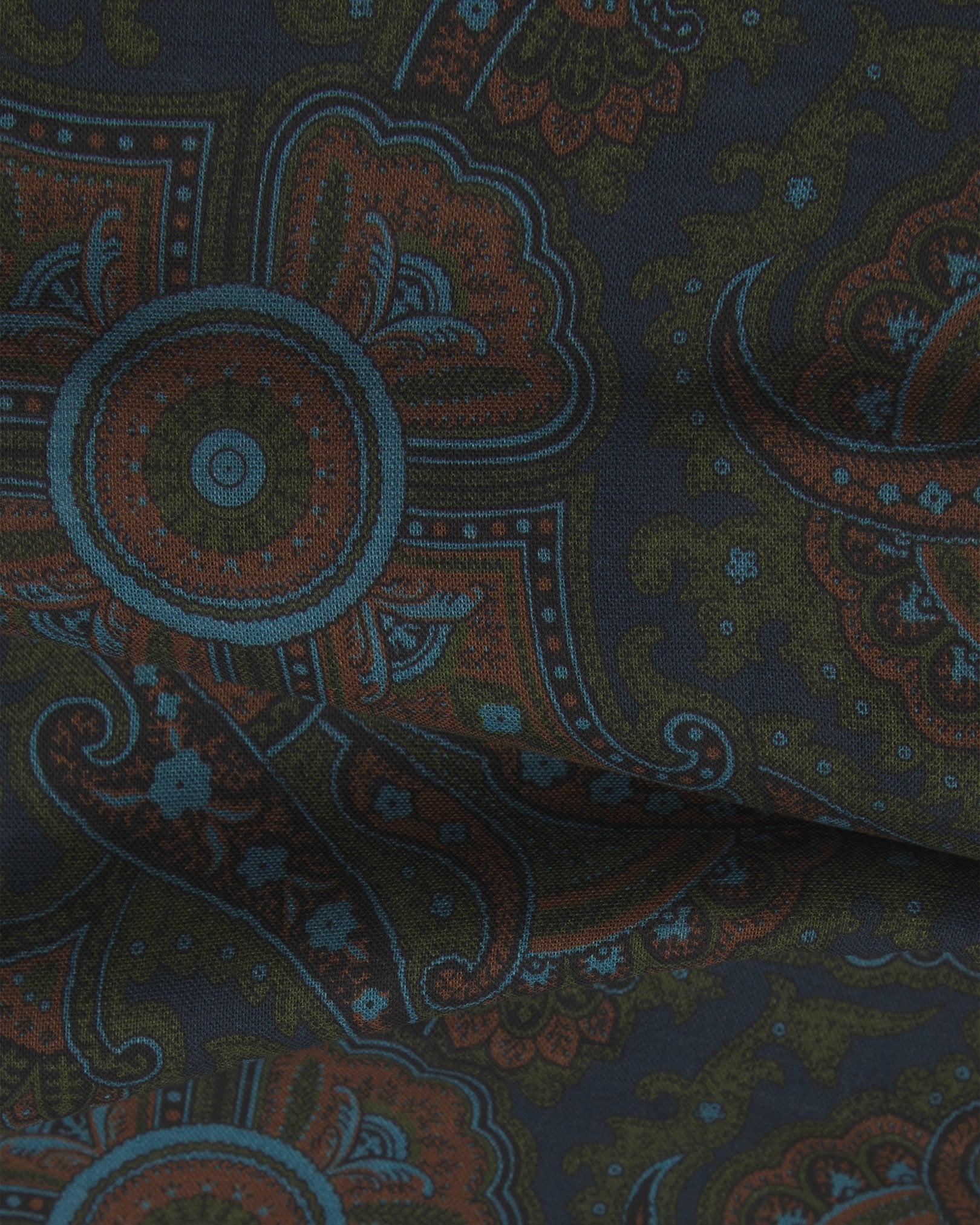 A flat and ruffled close-up view of the UK-made deep navy-blue paisley scarf. Clearly showing the premium silk and wool weave and the detailed red, blue and yellow paisley patterns against a red background.