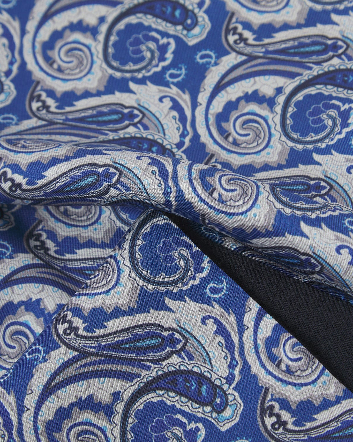 Ruffled close-up view of the Renton silk scarf, presenting a closer view of the silver, black and light blue paisley patterns.