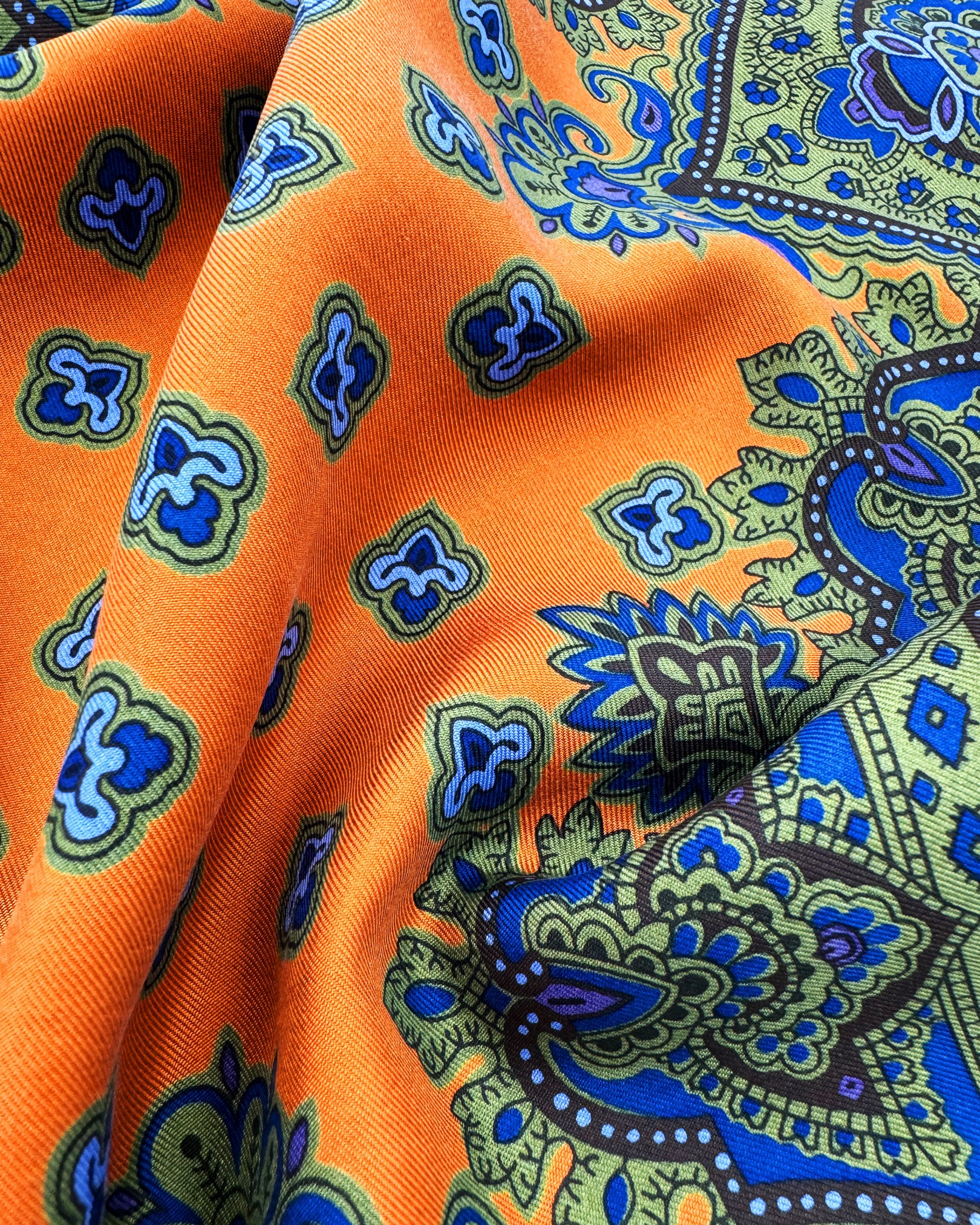 A ruffled close-up of the 'Ambleside' pocket square, presenting a closer view of the miniature fleur-de-lis patterns against the attractive lustre of the madder silk material. 