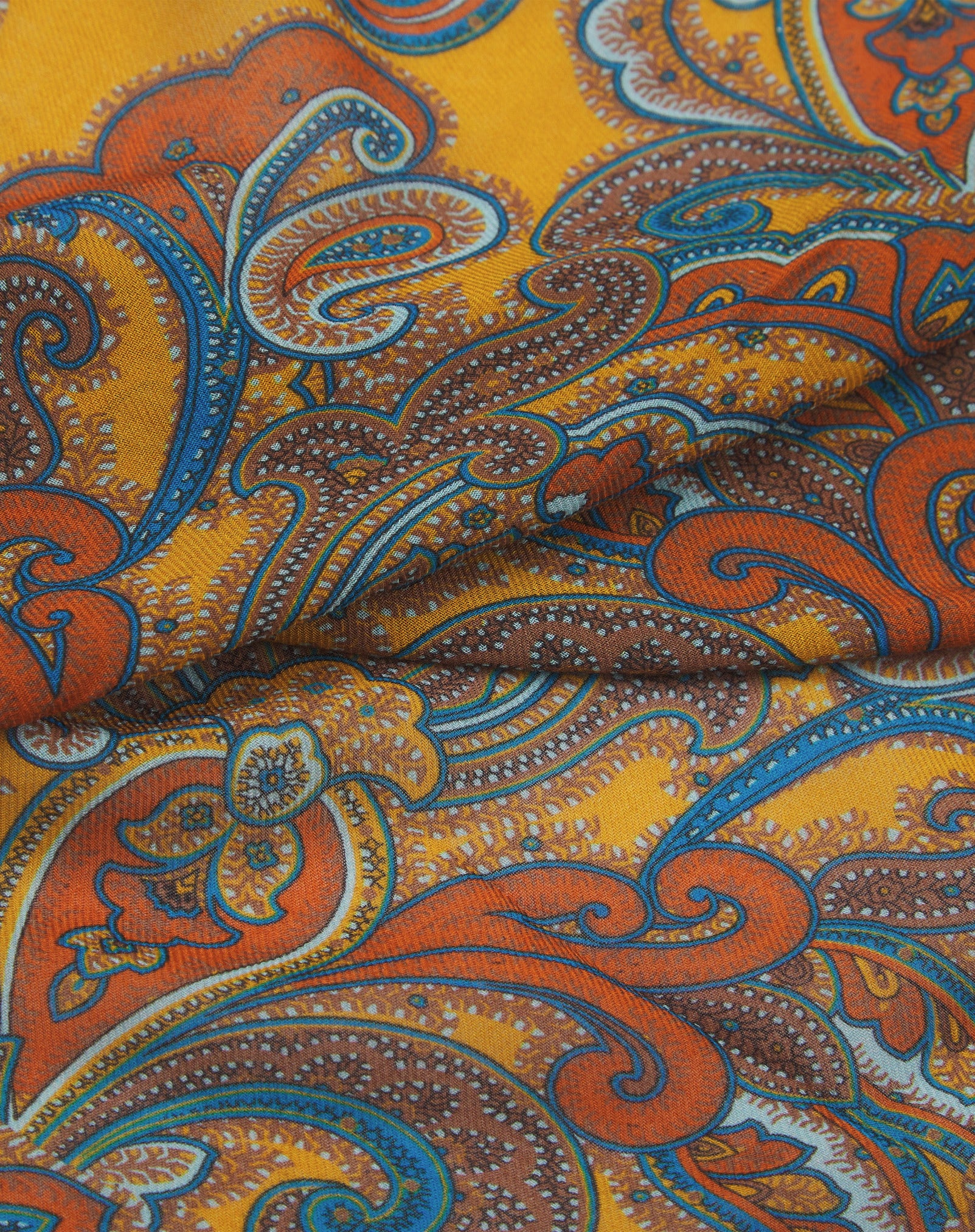 A ruffled close-up of the 'Carnaby' modal and wool bandana, presenting a closer view of the bright, paisley patterned design and modal weave.