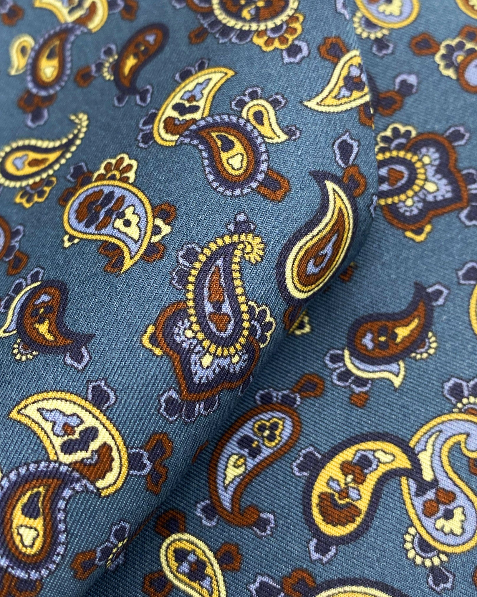 Ruffled close-up view of the Banff silk scarf, presenting a closer view of theblue, black and lemon yellow paisley patterns.