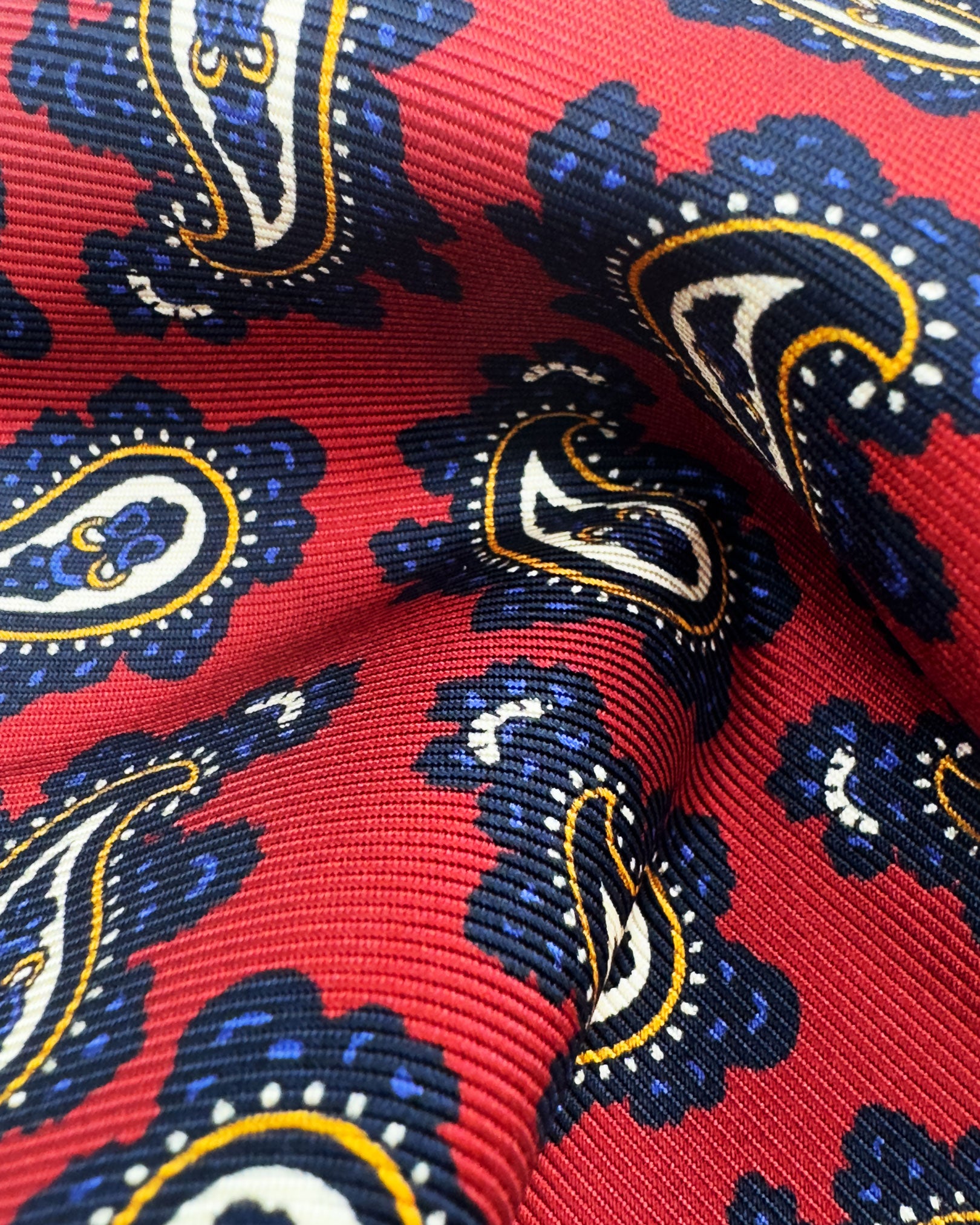 A ruffled close-up of the 'Binham' pocket square, presenting a closer view of the paisley patterns against the attractive lustre of the deadstock silk material. 
