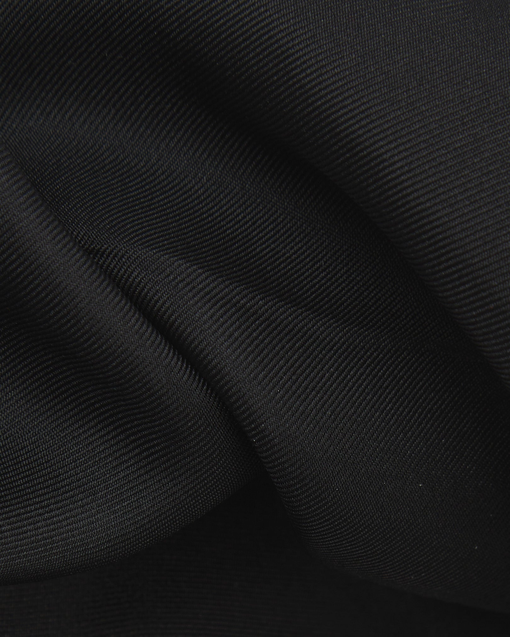 A ruffled close-up of the black silk pocket square from SOHO Scarves, showing the fine silk weave in greater detail.