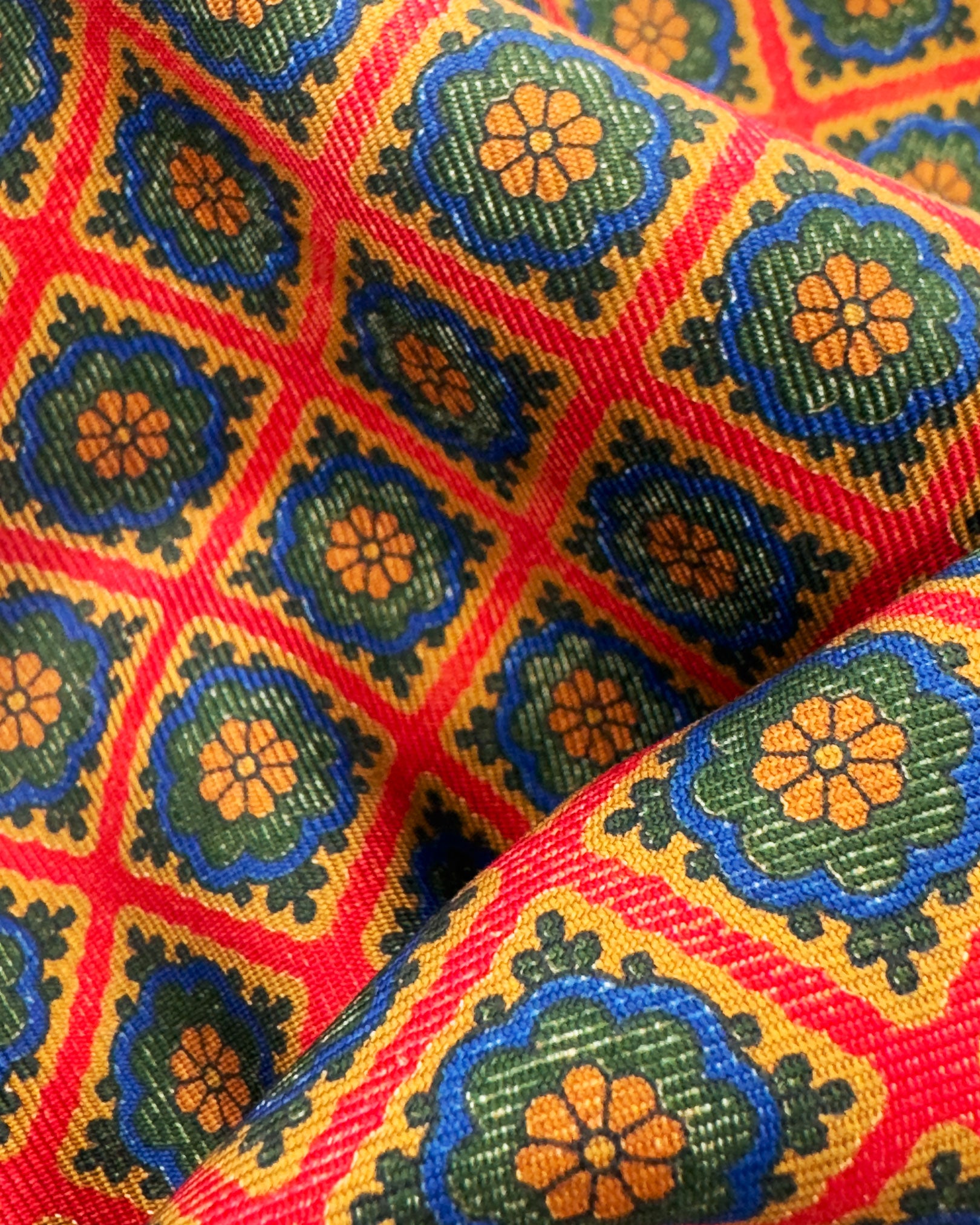 A ruffled close-up of the 'Bolsover' pocket square, presenting a closer view of the multicoloured floral grids against the attractive lustre of the deadstock silk material. 