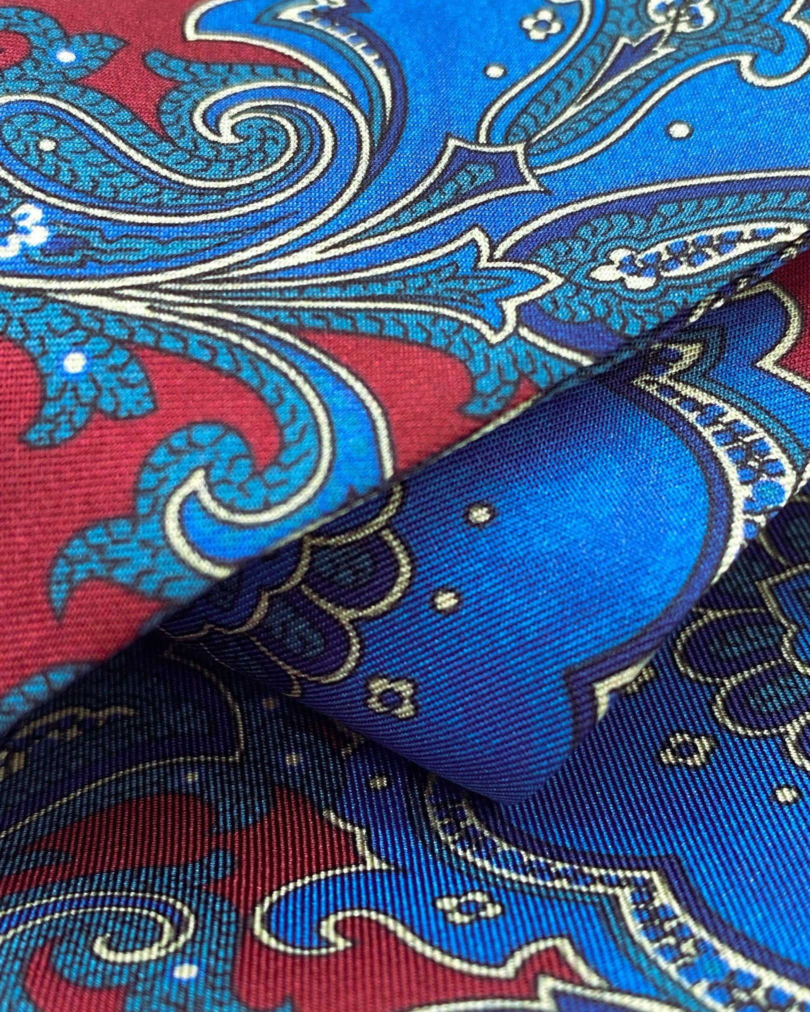 Ruffled close-up view of the 'Dean' silk aviator scarf, presenting a closer view of the swirls of blue paisley intertwined with abstract floral patterns and subtle lustre of the material.