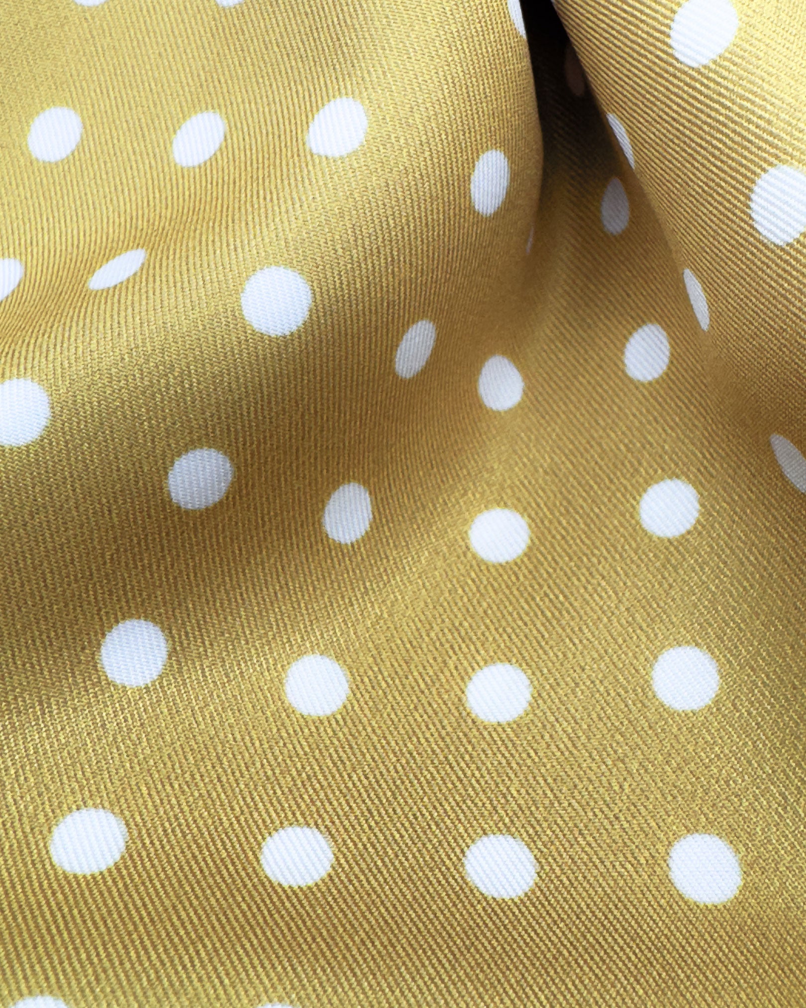 Ruffled close-up view of the 'Denman' polyester scarf, presenting a closer view of the golden yellow fabric with white dots 