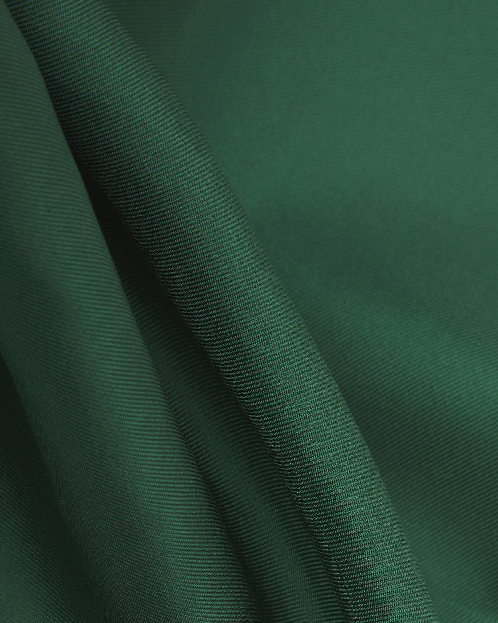 A ruffled close-up of the green silk pocket square from SOHO Scarves, showing the fine silk weave in greater detail.