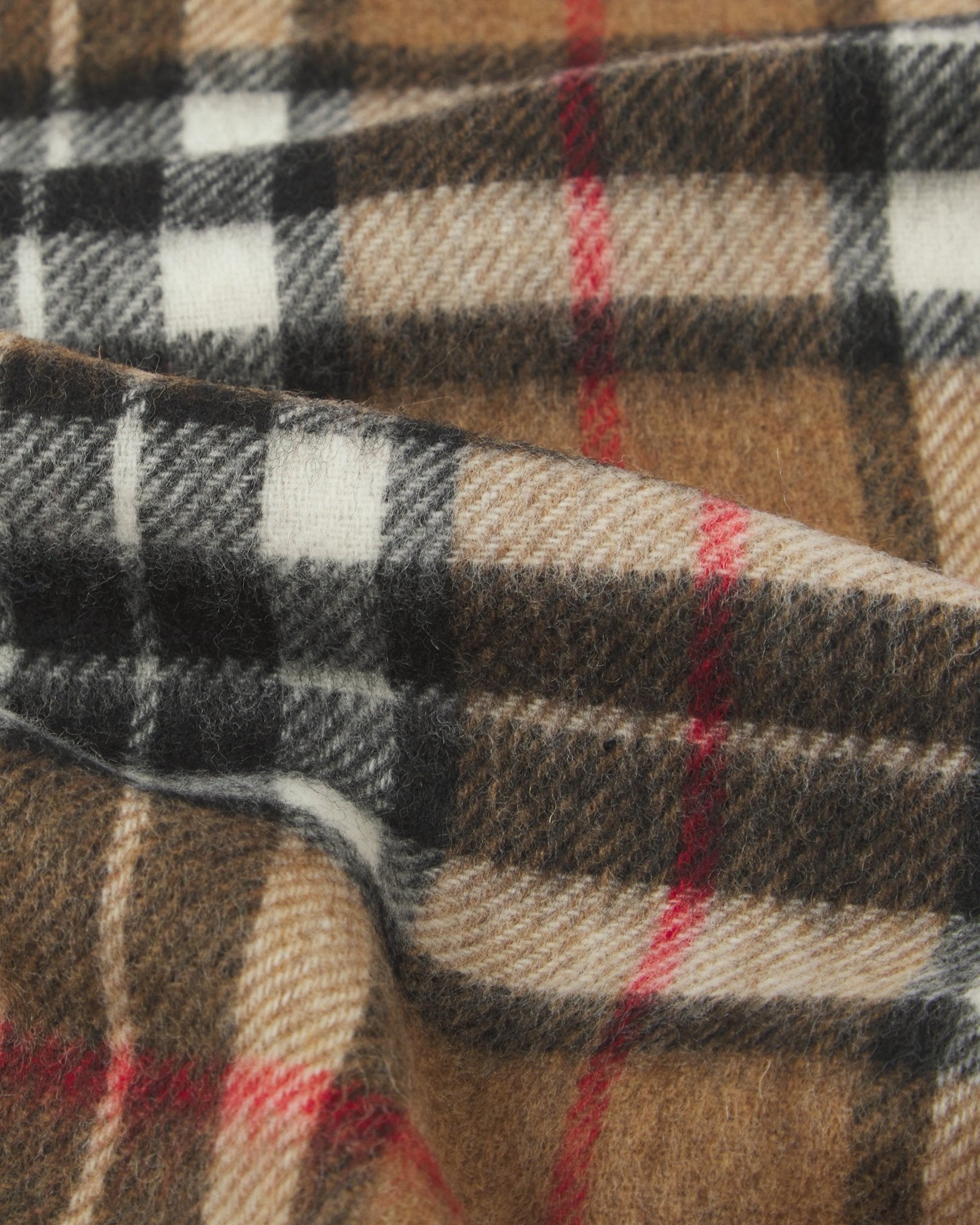 Ruffled close-up view of the UK-made, pure Merino wool 'Highlands' tartan in camel scarf, presenting a closer view of the camel, black, white, and red interlocking tartan pattern.