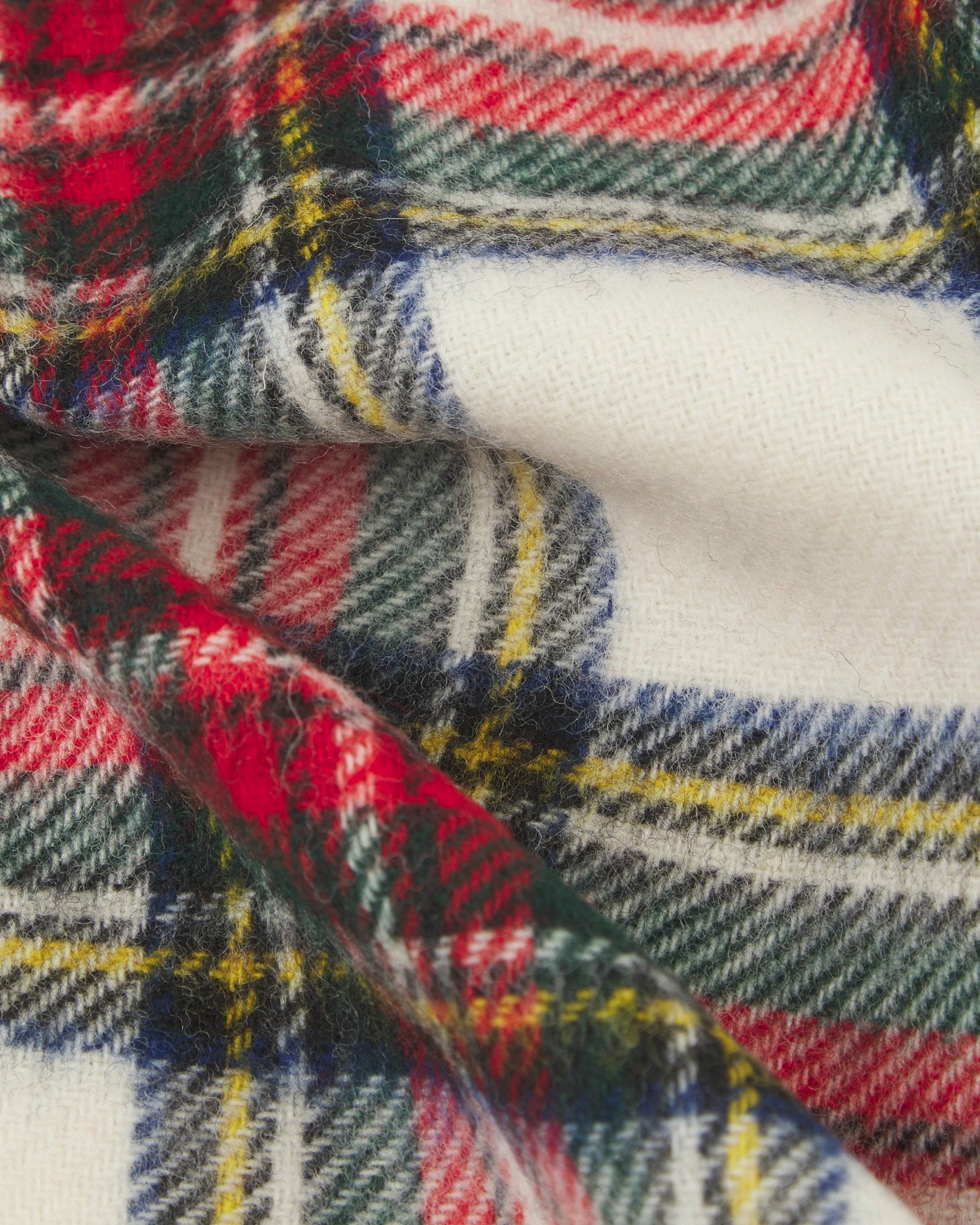 Ruffled close-up view of the UK-made, pure Merino wool 'Highlands' tartan dress in red scarf, presenting a closer view of the red, blue, green and yellow interlocking tartan pattern.