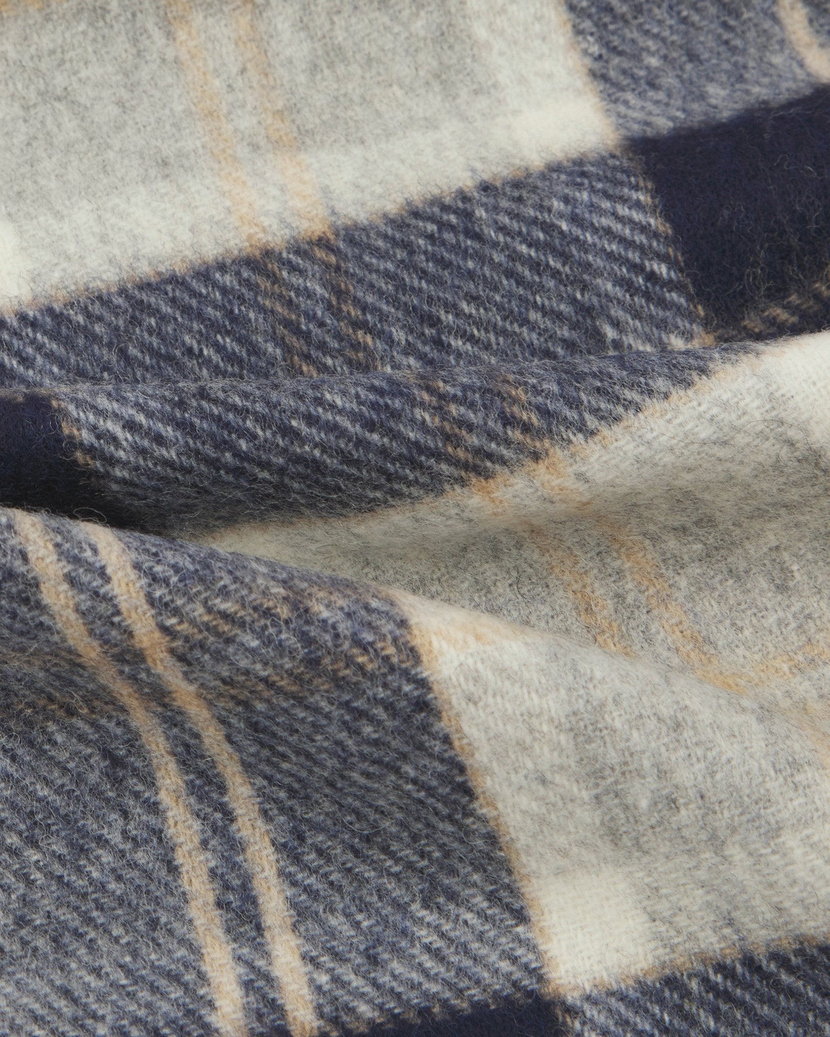 Ruffled close-up view of the UK-made, pure Merino wool 'Highlands' tartan in silver scarf, presenting a closer view of the camel, grey, and black interlocking tartan pattern.