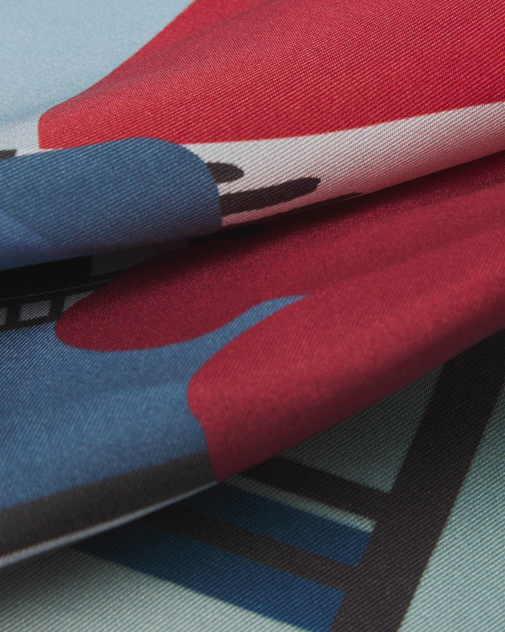 A ruffled close-up of the 'House' silk pocket square from SOHO Scarves, showing overlapping elements of the Japanese style building with rising sun and Mount Fuji background.