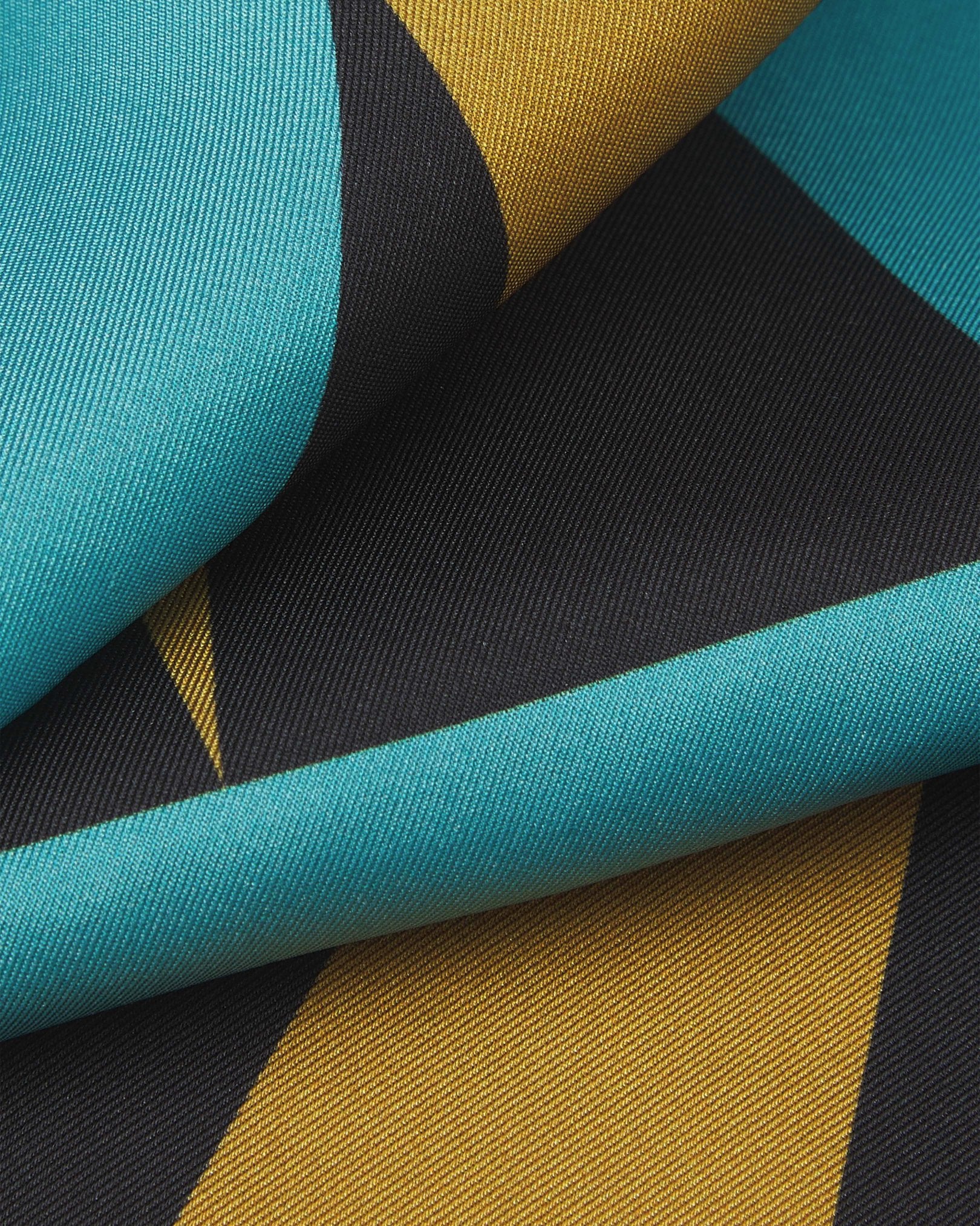 A ruffled close-up of the 'Leipzig' pocket square, presenting a closer view of the interplay of blue, grey and yellow triangles.