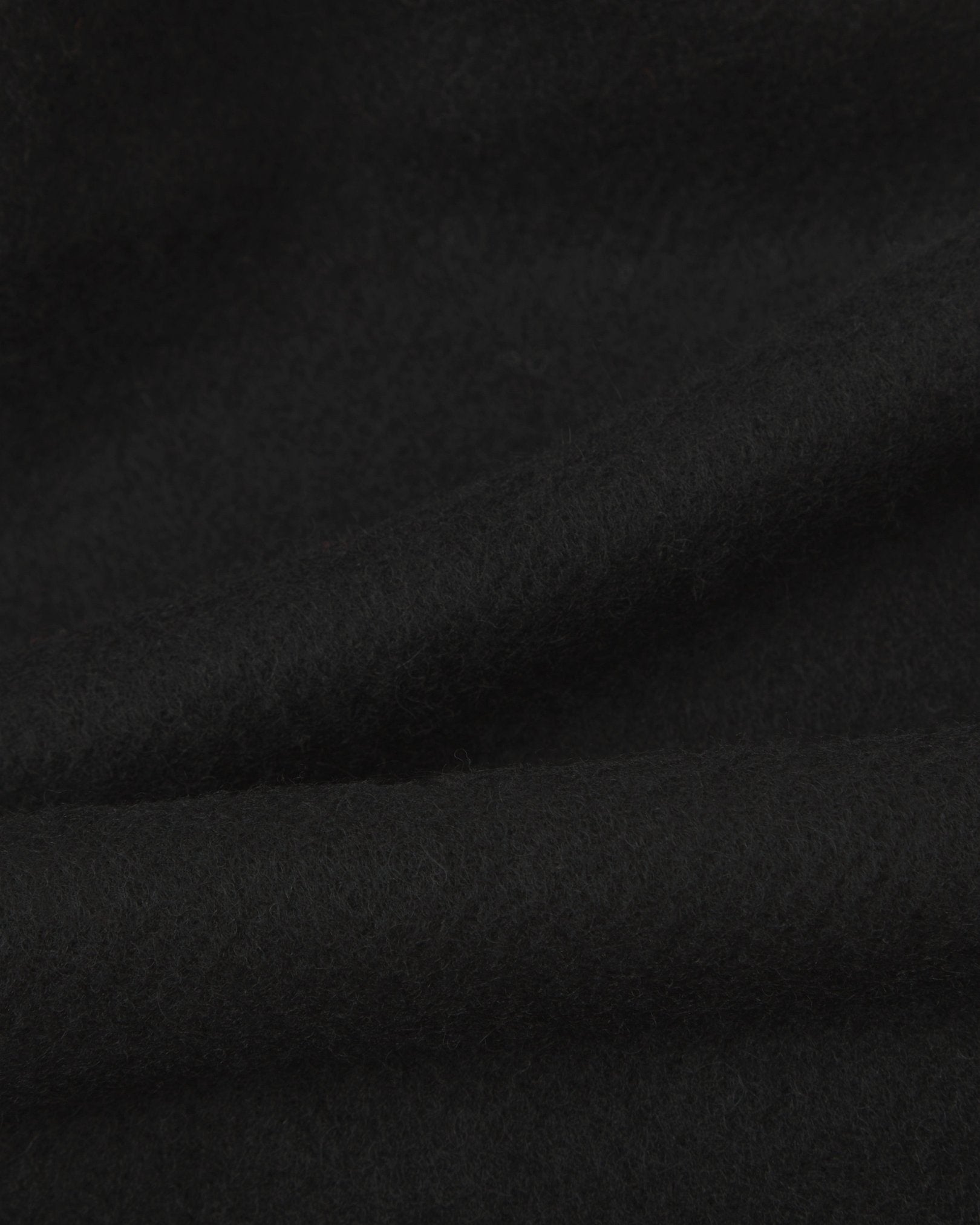 Ruffled close-up view of the UK-made, pure Merino wool 'lowlands' tartan dress in black scarf, presenting a closer view of the premium woollen fabric.