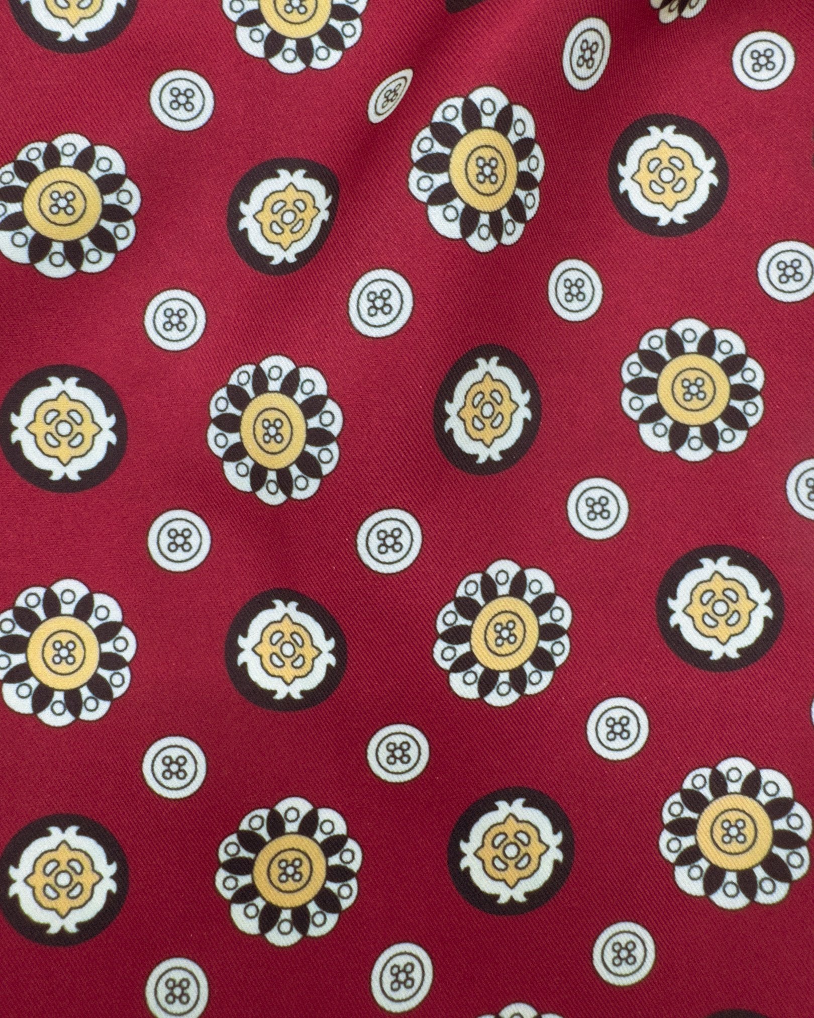 A closer, ruffled view of the red scarf with yellow, black and cream 'button' geometric patterns.