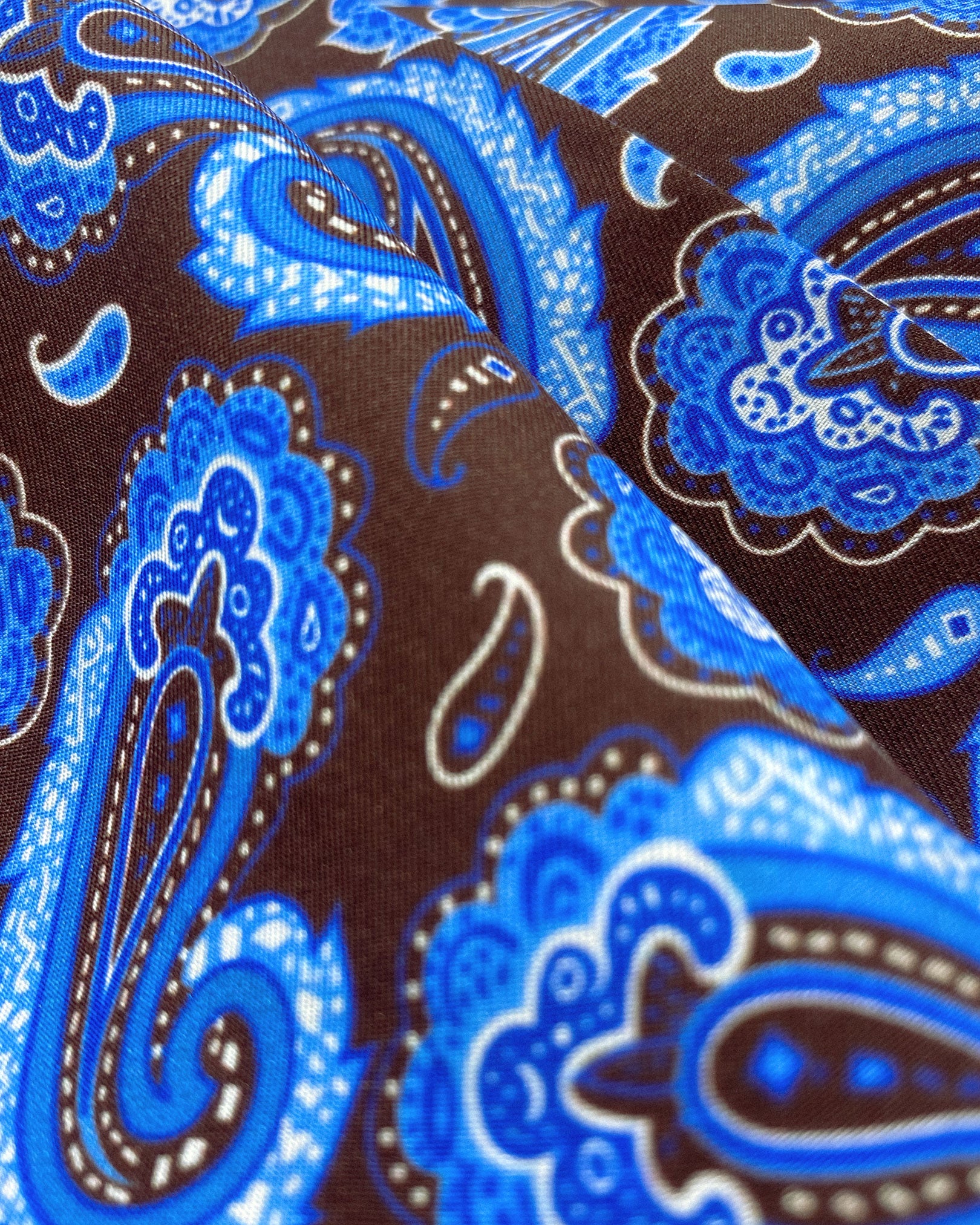 Ruffled close-up view of the 'Myers' silk aviator scarf, presenting a closer view of the powder-blue paisley swirls and subtle lustre of the silk material.