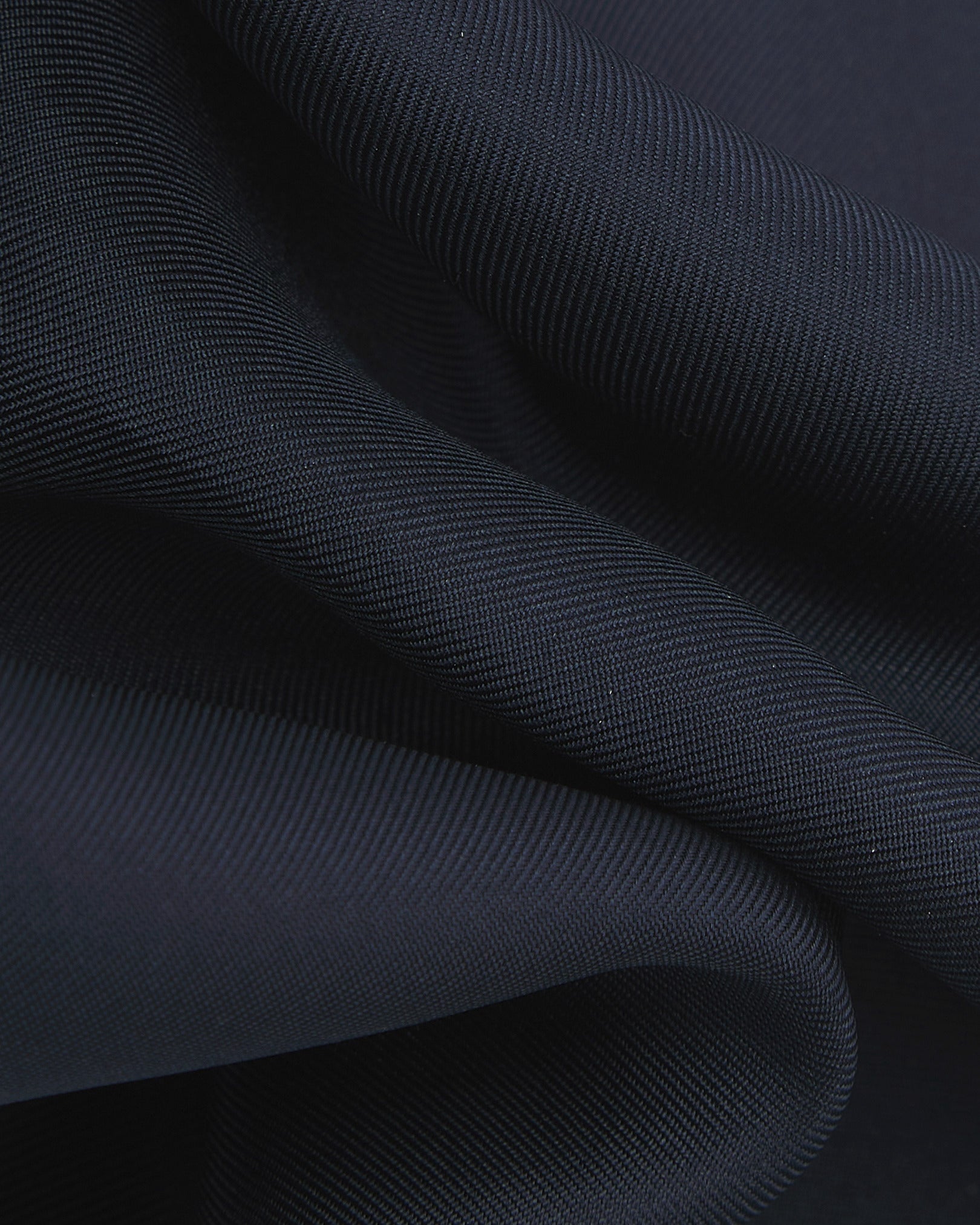 A ruffled close-up of the navy-blue silk pocket square from SOHO Scarves, showing the fine silk weave in greater detail.