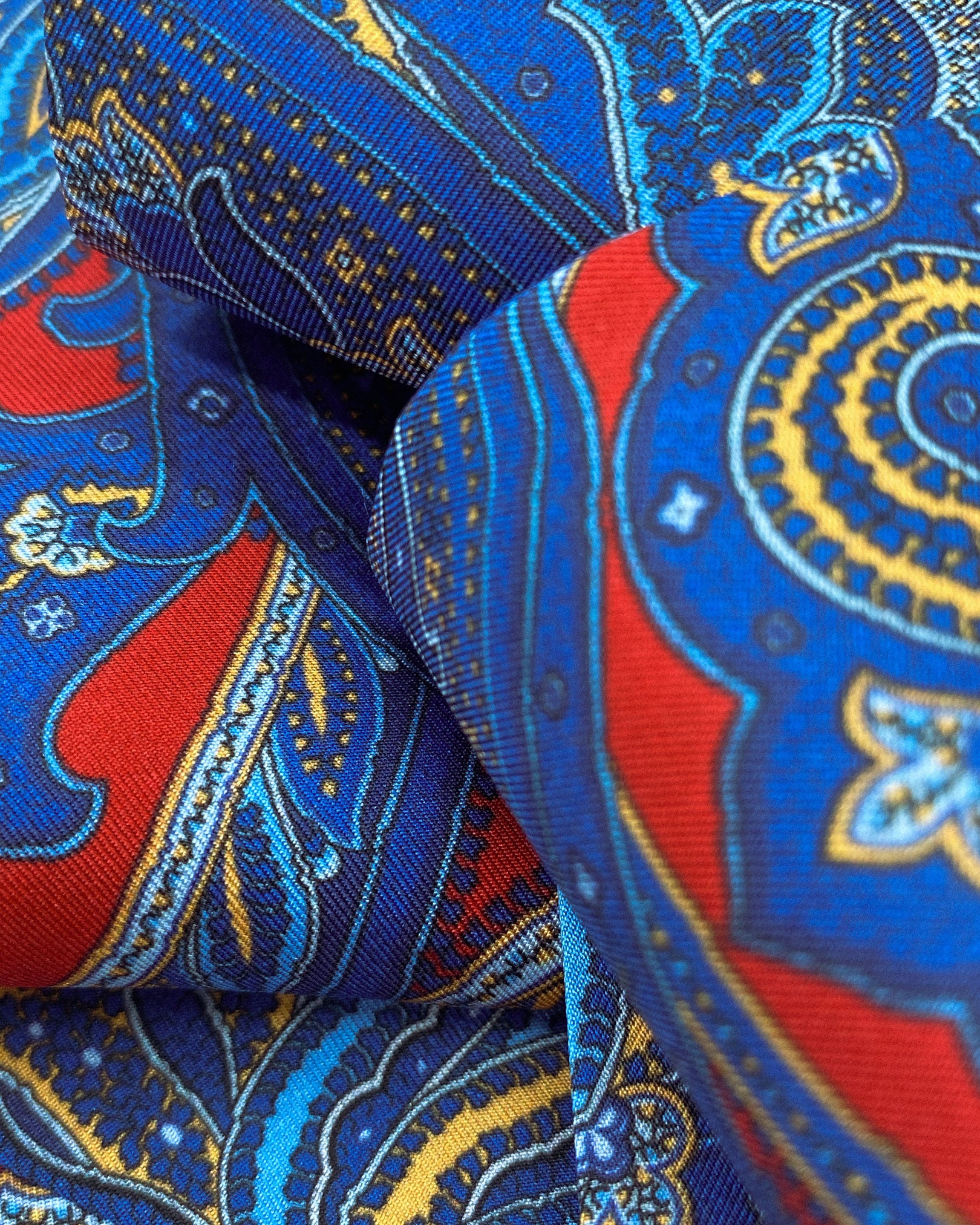 Ruffled close-up view of the Oxford silk neckerchief, presenting a closer view of the intricate swirls of blue and red paisley and appealing lustre of the material.
