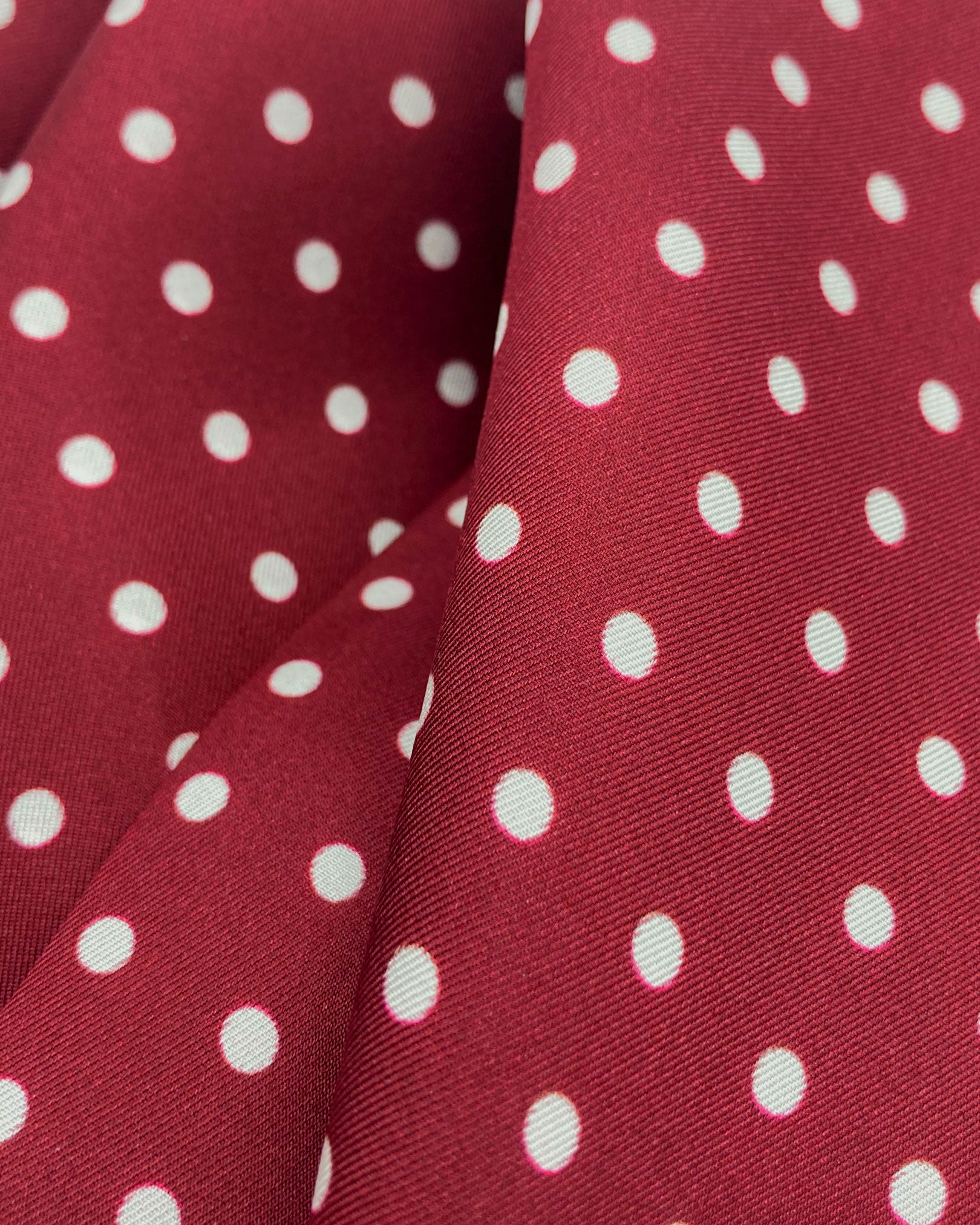Ruffled close-up view of the Sapporo silk scarf, presenting a closer view of the polka dot design in deep maroon with white dots and appealing lustre of the material.