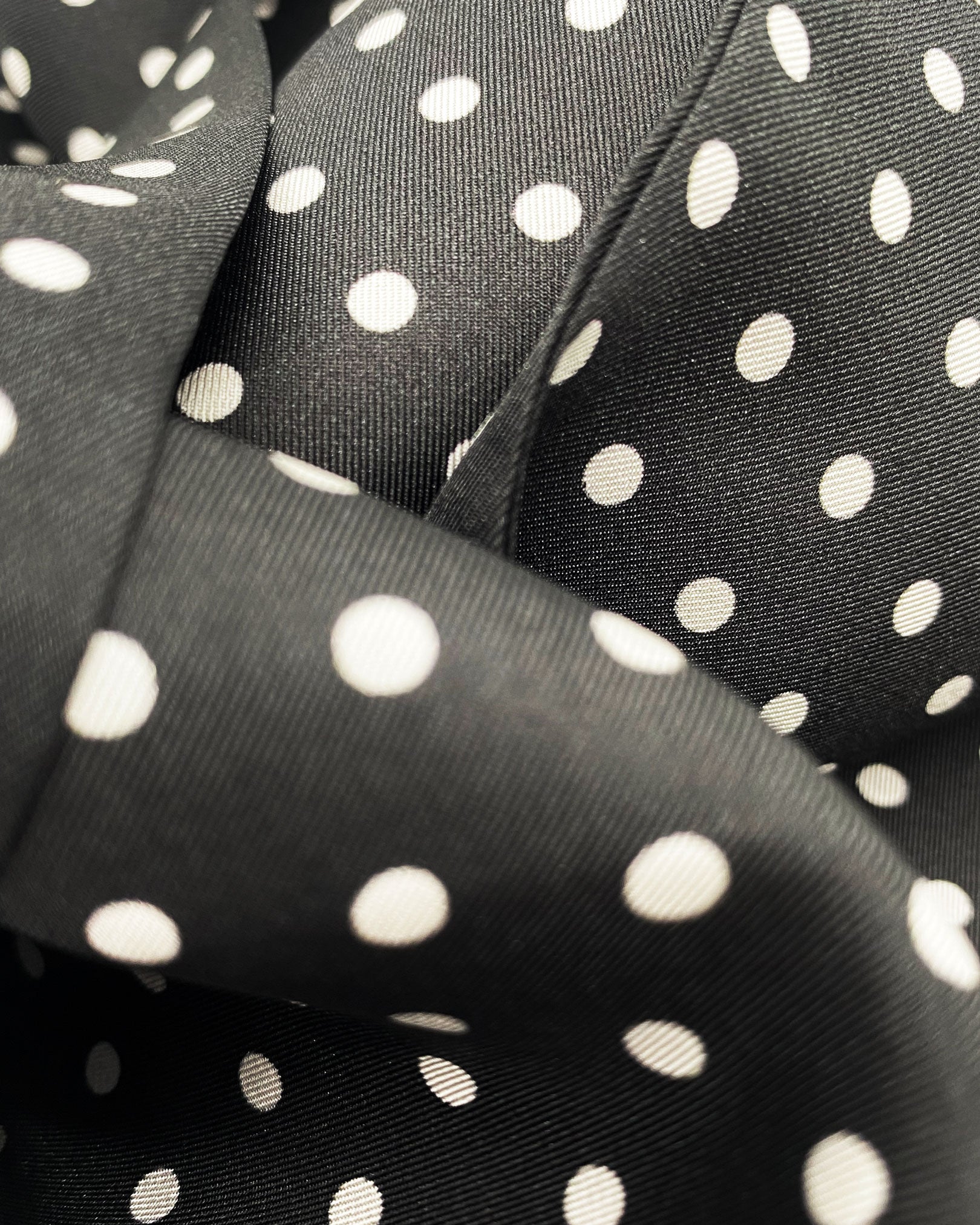 Ruffled close-up view of the 'Shinagwa' silk scarf, presenting a closer view of the white polka dot pattern and subtle lustre of the material.
