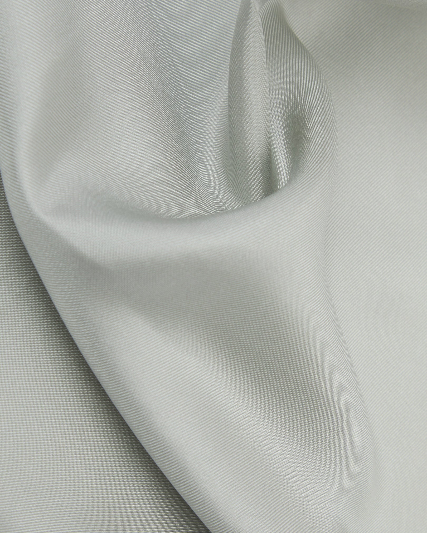 A ruffled close-up of the silver silk pocket square from SOHO Scarves, showing the fine silk weave in greater detail.