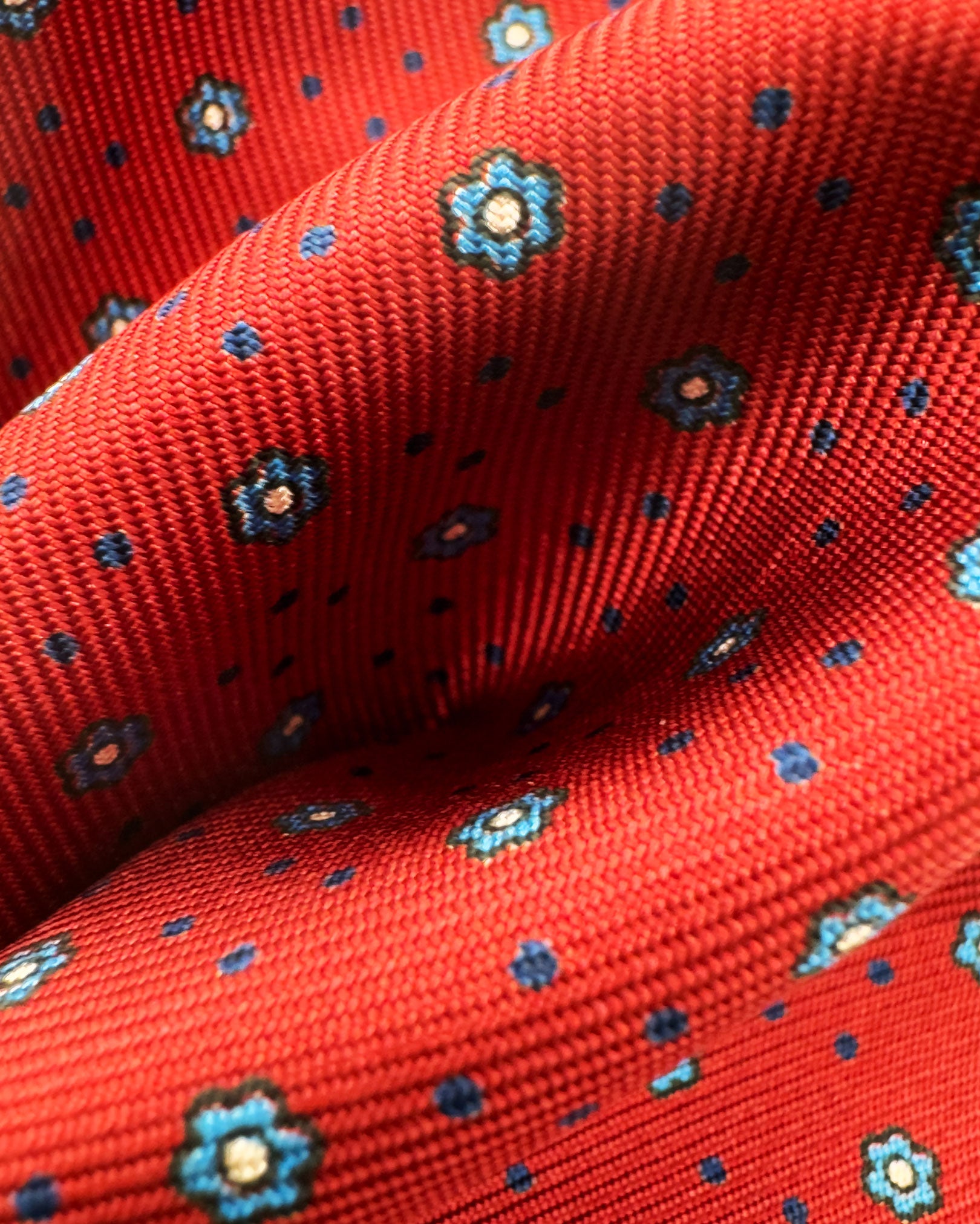 A ruffled close-up of the 'Studley' pocket square, presenting a closer view of the blue floral patterns against the attractive lustre of the deadstock silk material. 