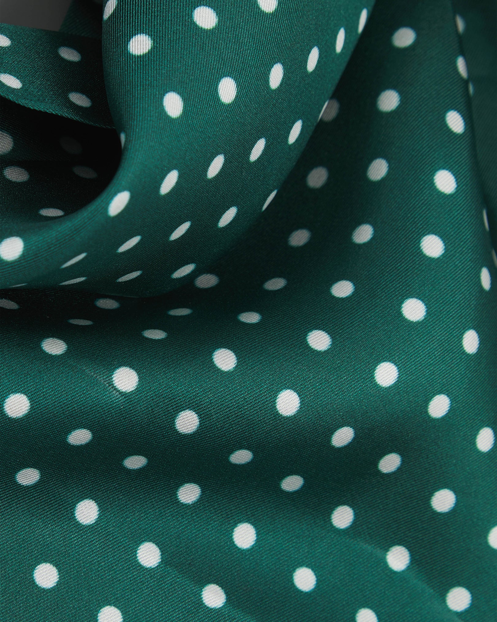 A flat and ruffled view of the 'Westminster Rg' silk scarf presenting a closer view of the silk fabric and the white polka-dot patterns.