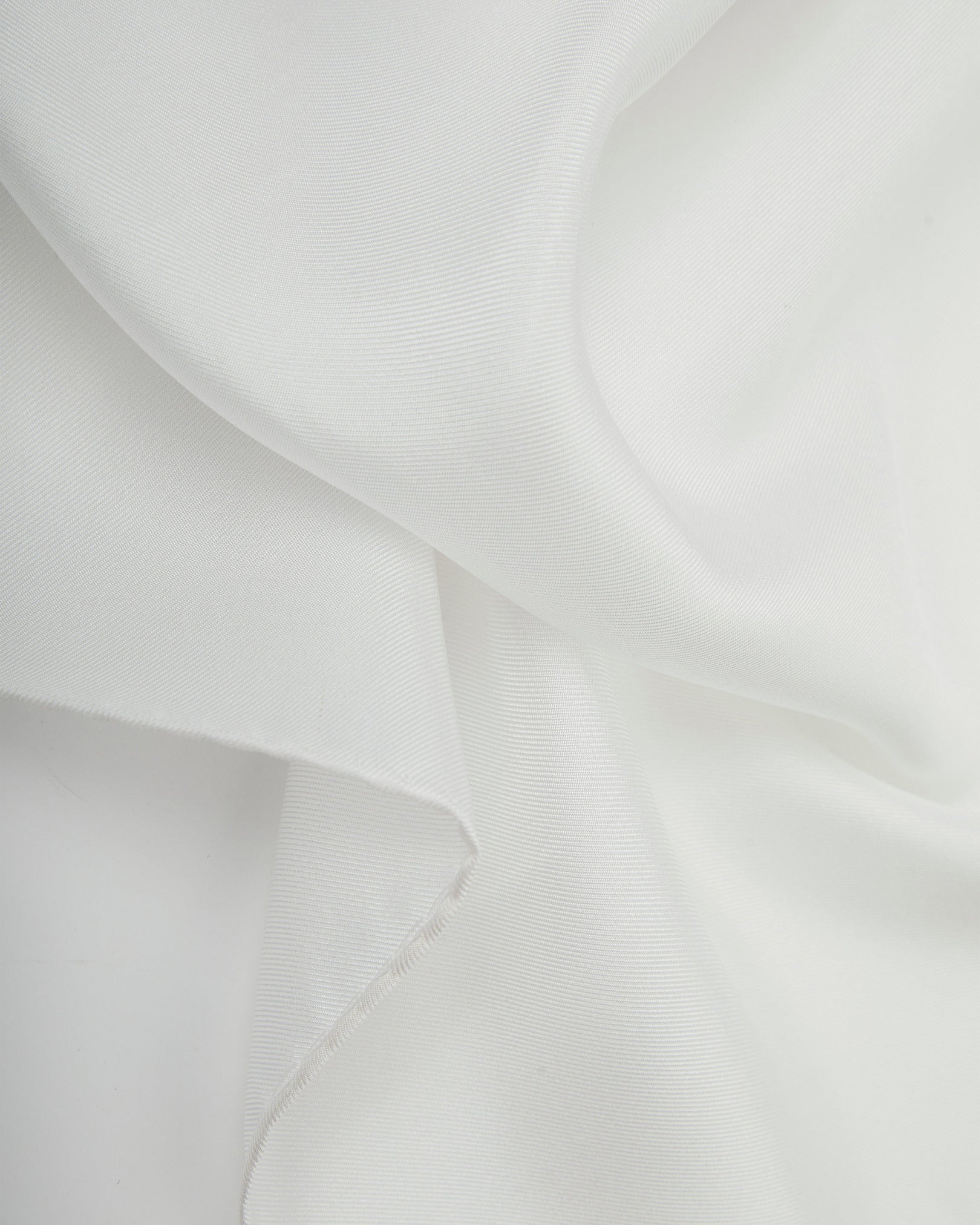 A ruffled close-up of the white silk pocket square from SOHO Scarves, showing the fine silk weave in greater detail.