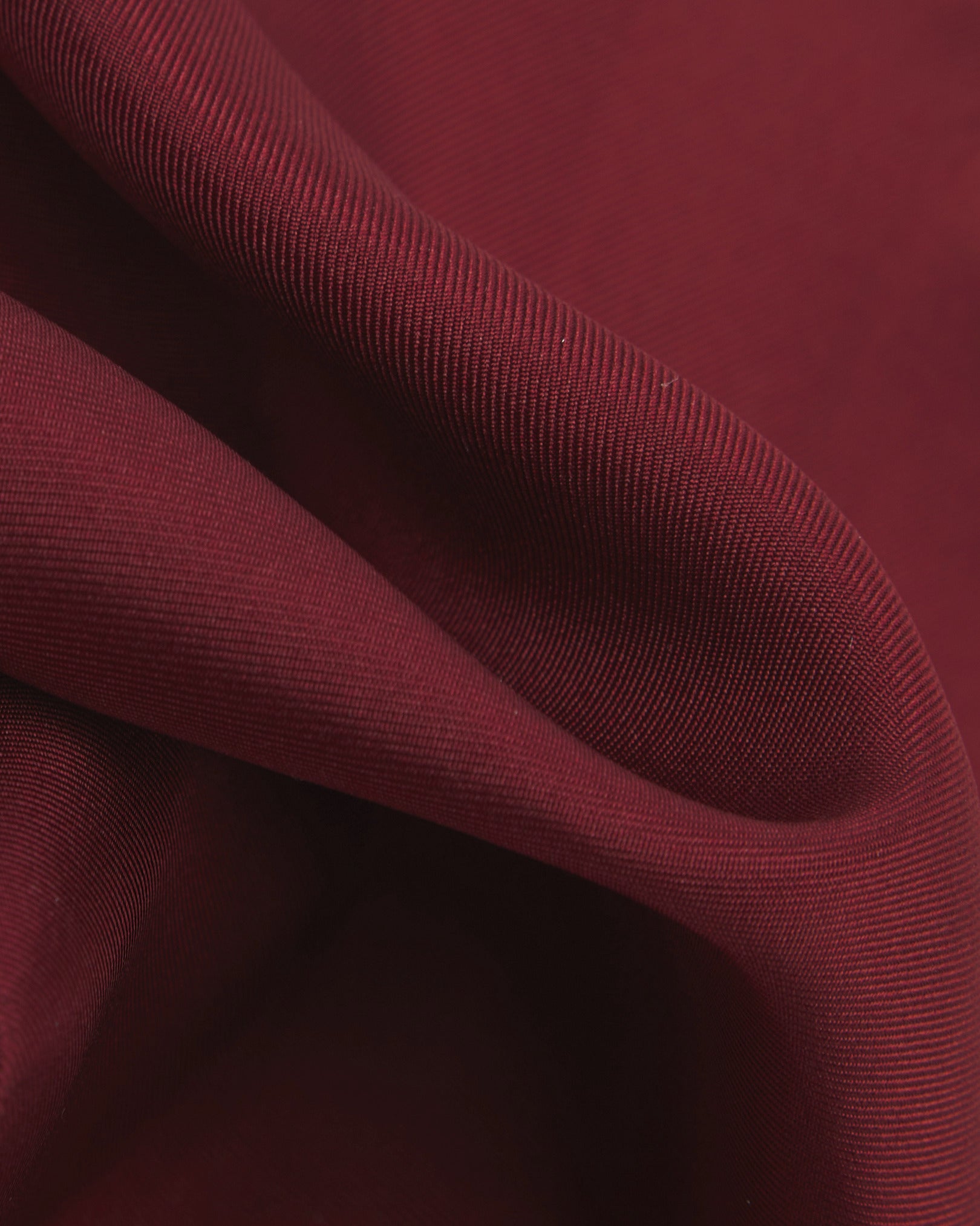 A ruffled close-up of the wine-red silk pocket square from SOHO Scarves, showing the fine silk weave in greater detail.