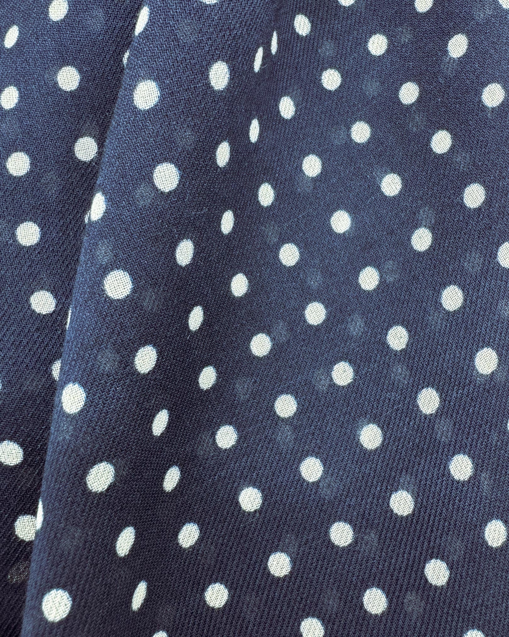 A flat, close up view of 'The Westminster' wide scarf. Clearly showing the modal and wool fabric and attractive white polka dot pattern against a navy-blue background.