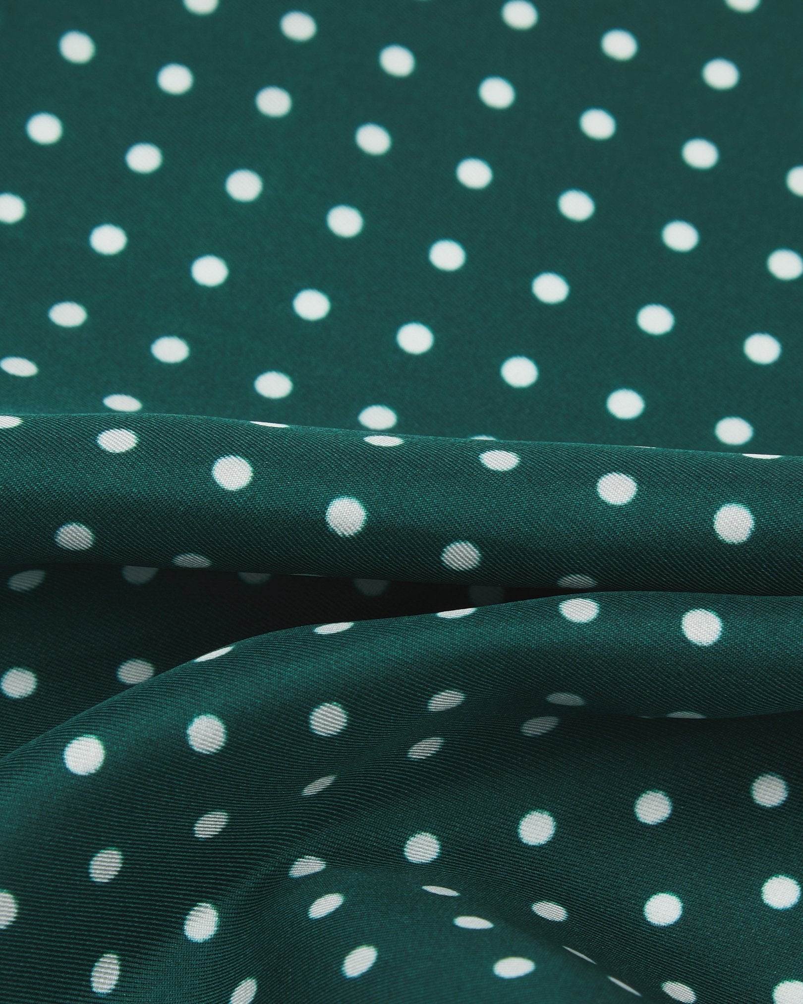 A ruffled close-up of the 'Westminster Rg' pocket square, presenting a closer view of the white polka dots against the attractive lustre of the racing green silk material. 