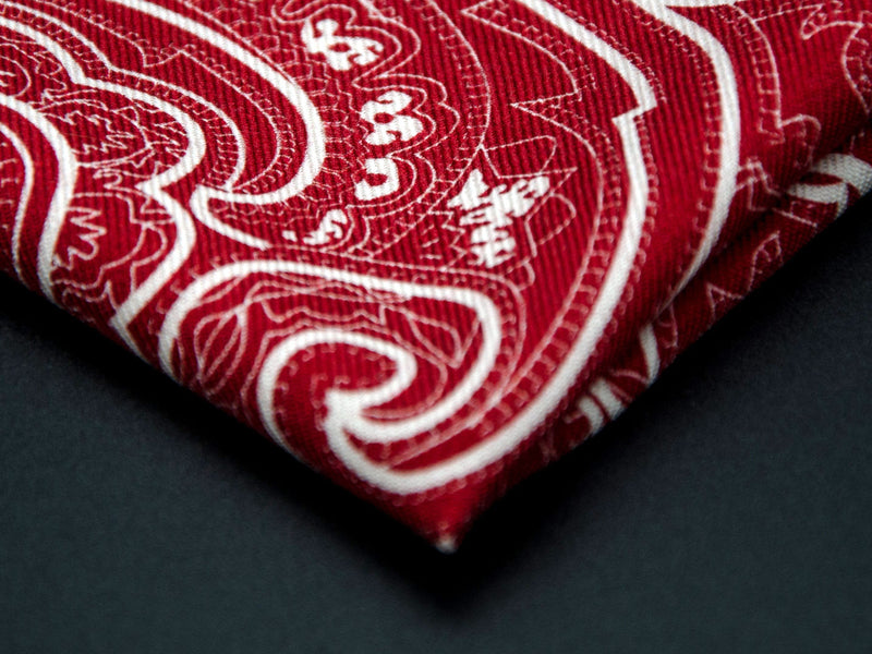 Close-up of a quarter point of the 'Kalamaja' red pocket square, providing clear view of the wool weave and an even closer look at a paisley segment.