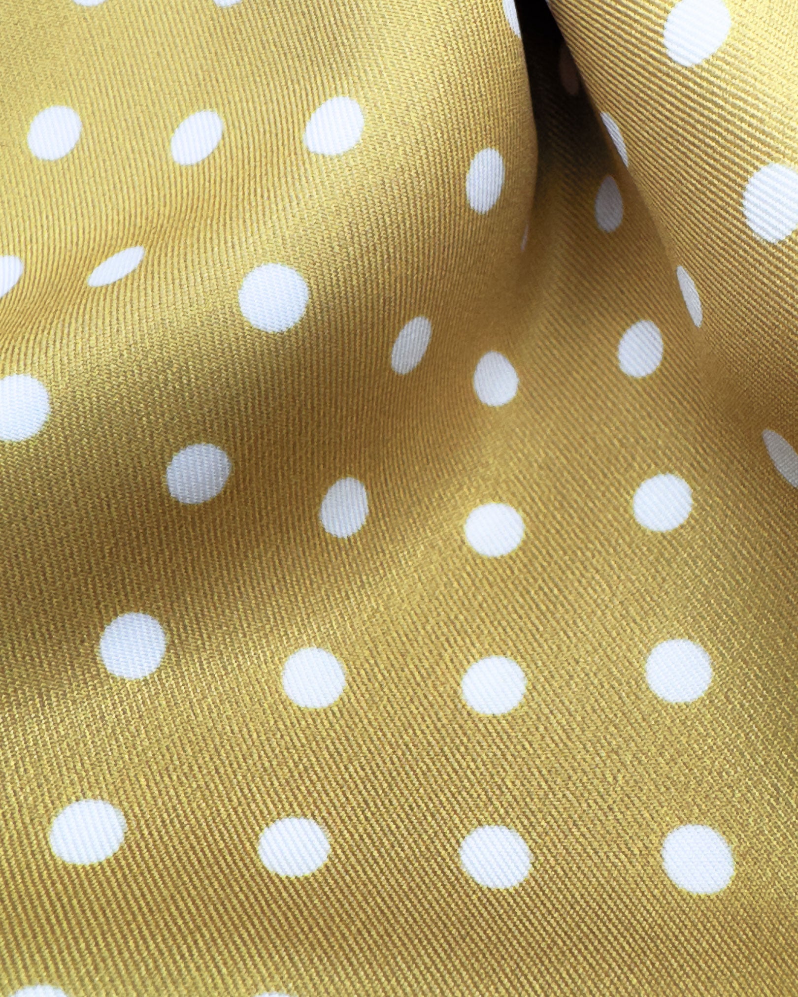 A ruffled close-up of the 'Denman' silk double ascot, presenting a closer view of the gold silk fabric and the white polka-dot patterns.